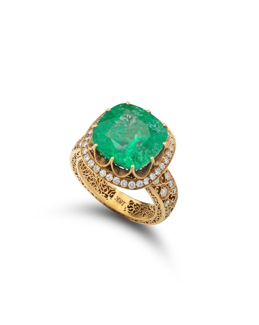 Gold ring with intricate engravings, featuring a large oval emerald gemstone surrounded by small diamonds.