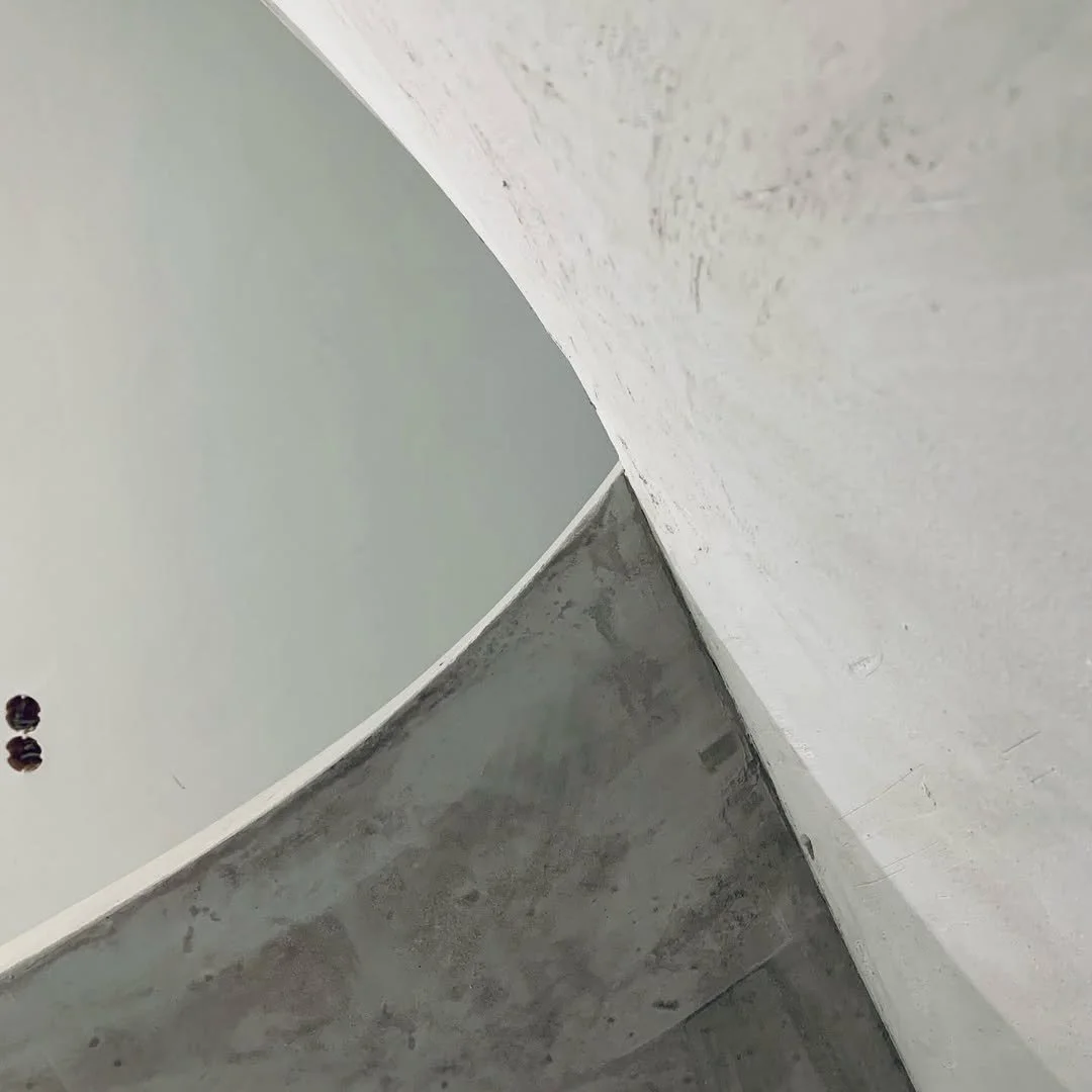 Nahaufnahme einer Ecke in einem Gebäude mit einer weißen Wand, einer grauen Wand und einer weißen Decke, die auf einen Baustil oder eine Renovierung hinweisen könnte.