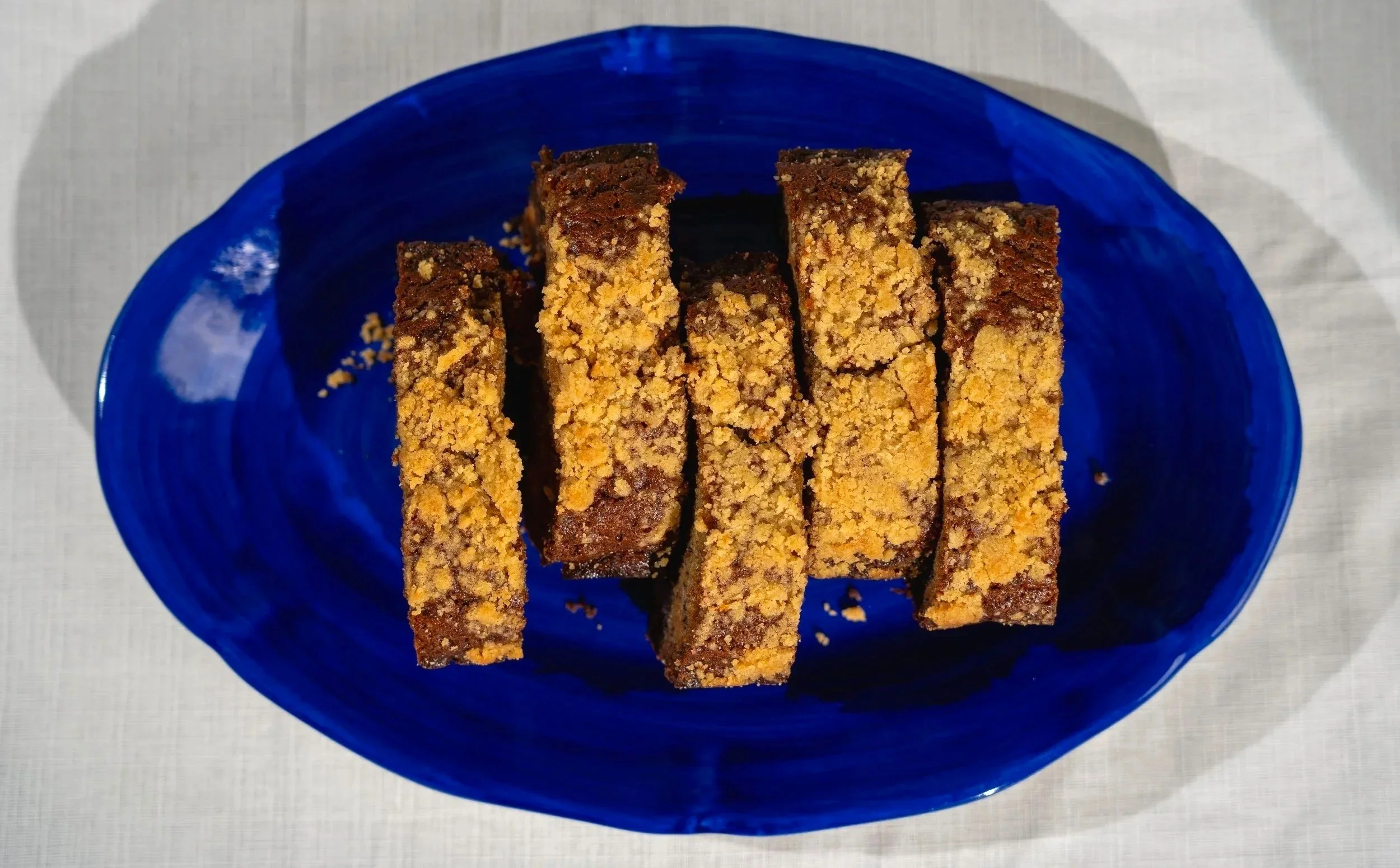 Six slices of banana bread with a crumbly topping on a blue oval plate