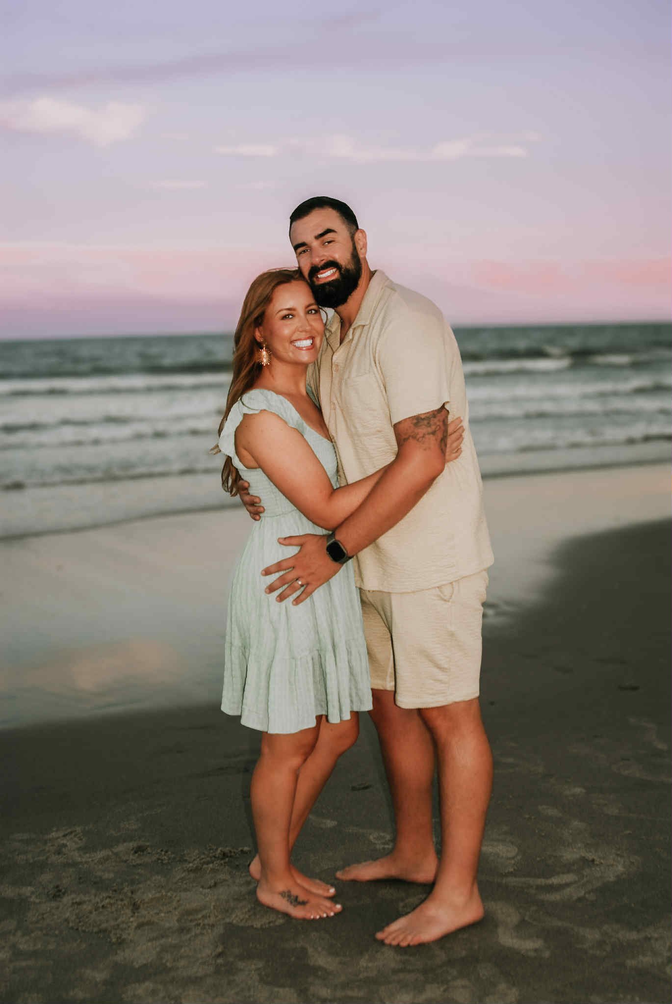 “Couples beach portrait by Faith K Photography in Myrtle Beach, SC featuring a smiling couple embracing at sunset with ocean waves and soft pink sky in the background.”