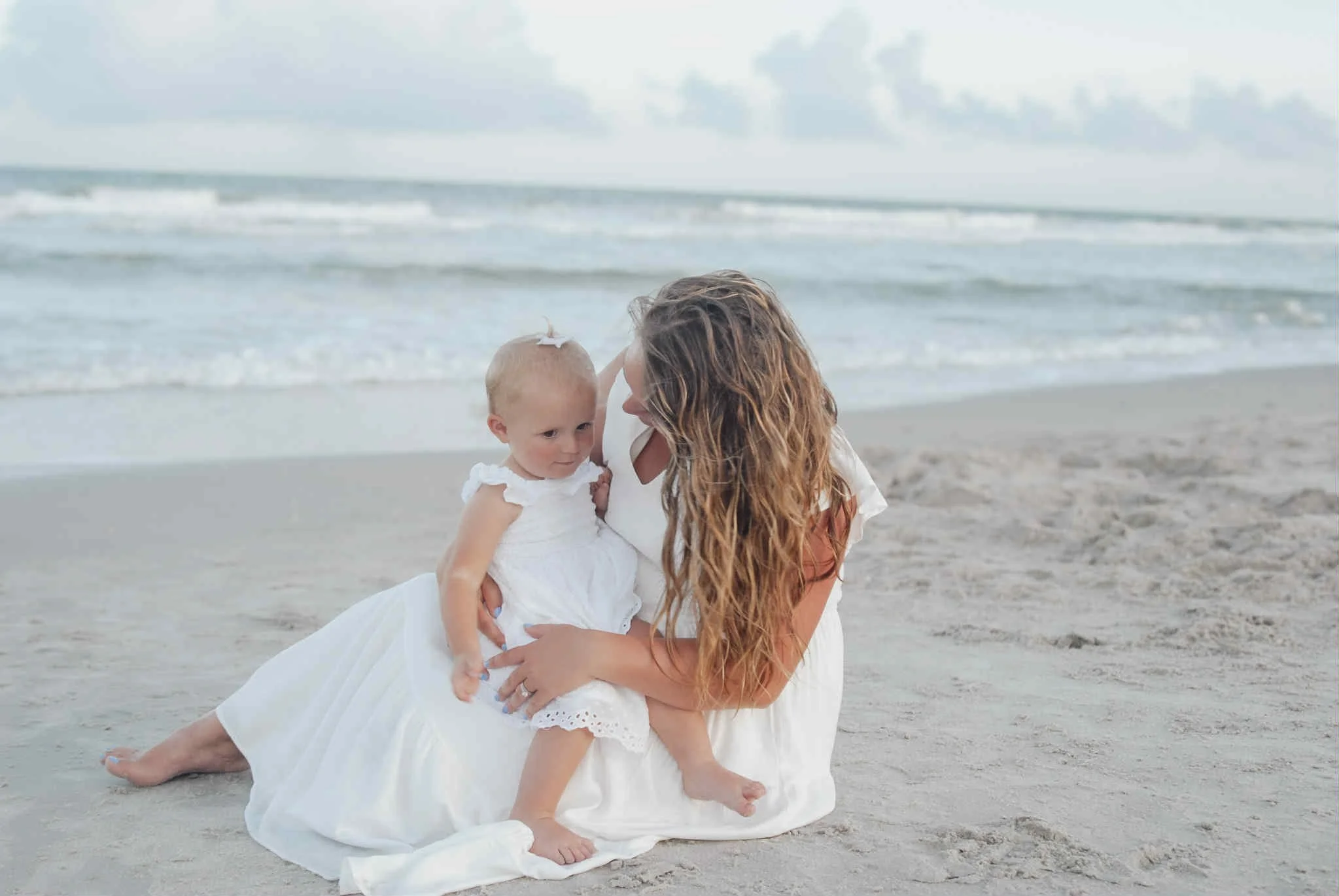 “Coastal motherhood session by Faith K Photography in Myrtle Beach South Carolina featuring mom and baby on sandy beach.”