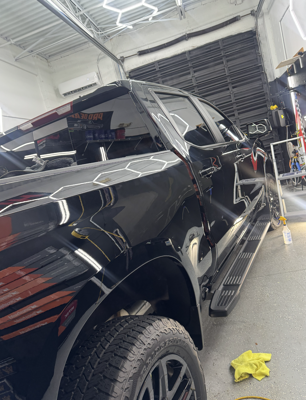 Black pickup truck in a garage with cleaning supplies nearby.