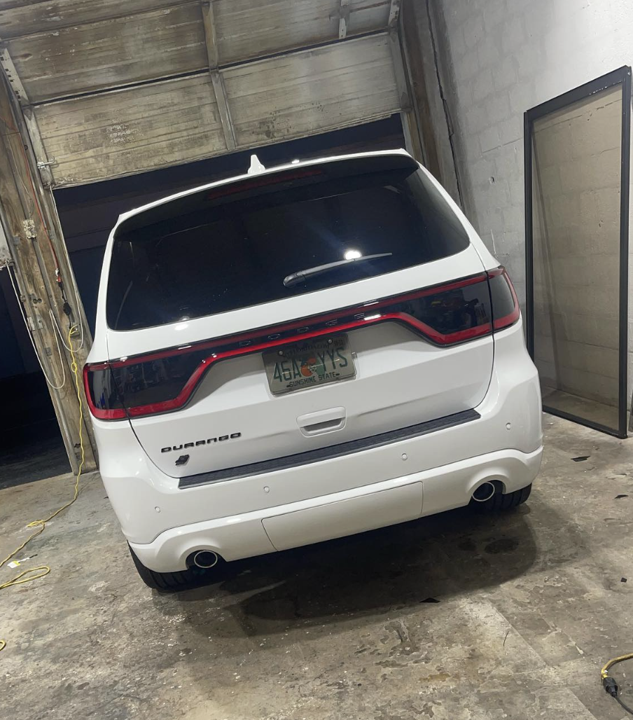 White Dodge Durango parked inside a garage with a Florida license plate and a tinted rear window.