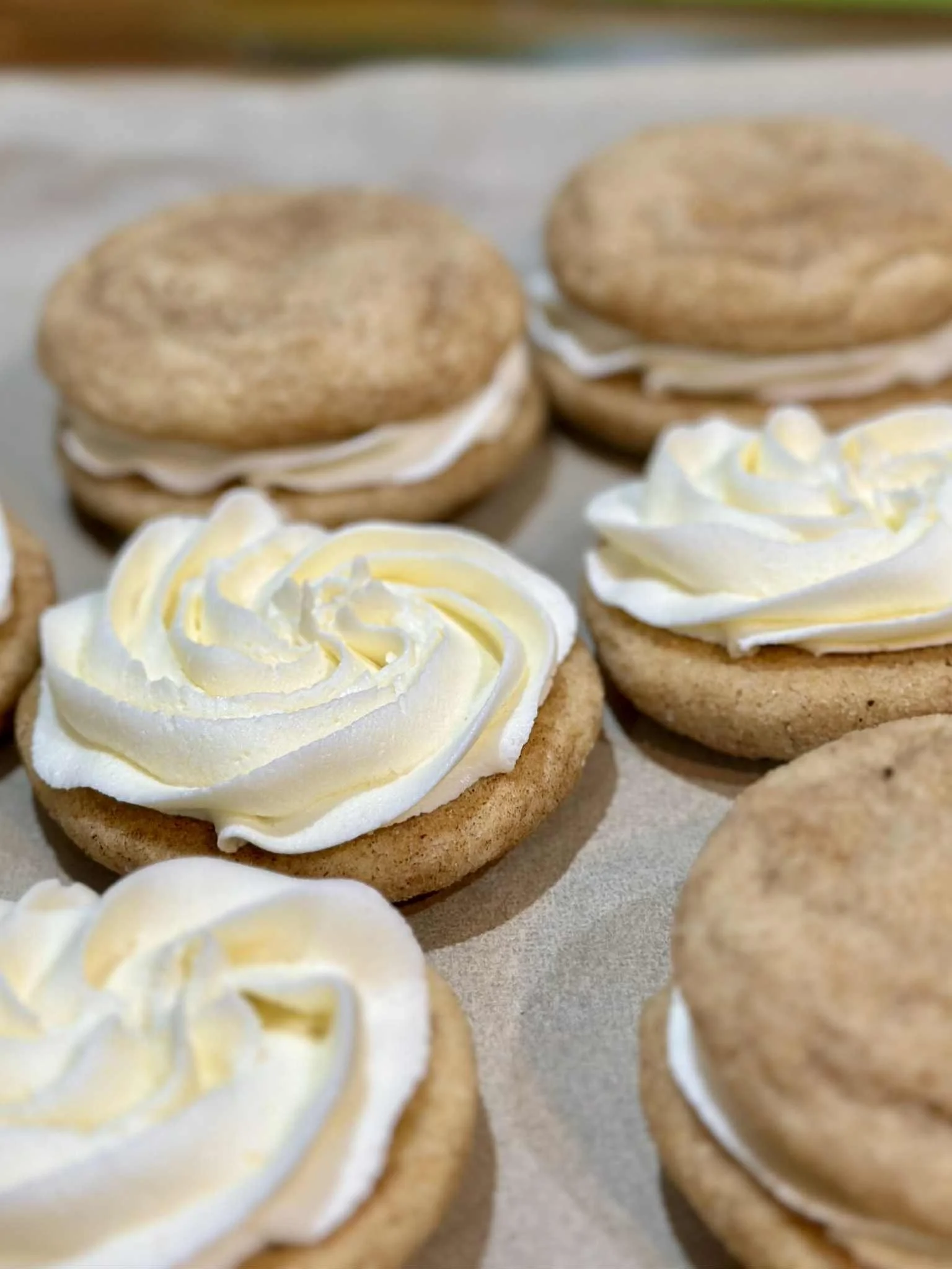 Assorted cookies with cream frosting, some with sandwich layers and others with piped frosting on top.