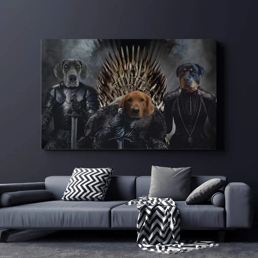 A framed picture of three dogs with human-like outfits sitting on a throne resembling the Iron Throne from Game of Thrones, hanging above a modern gray couch with black and white chevron-patterned pillows and a throw blanket.