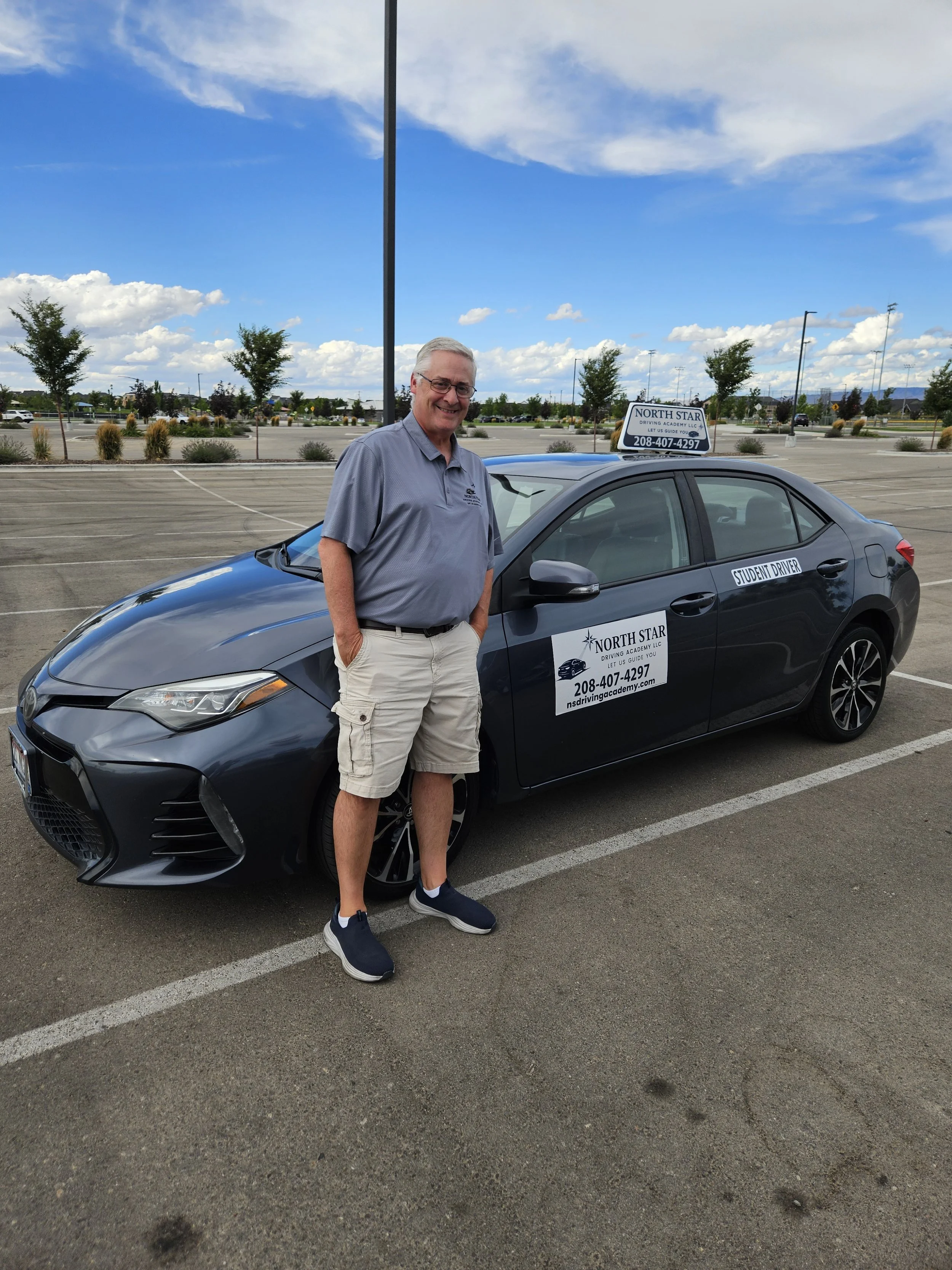 Driving instructor Nick Schamber smiling and standing in front of a North Star Driving Academy driver's education car.