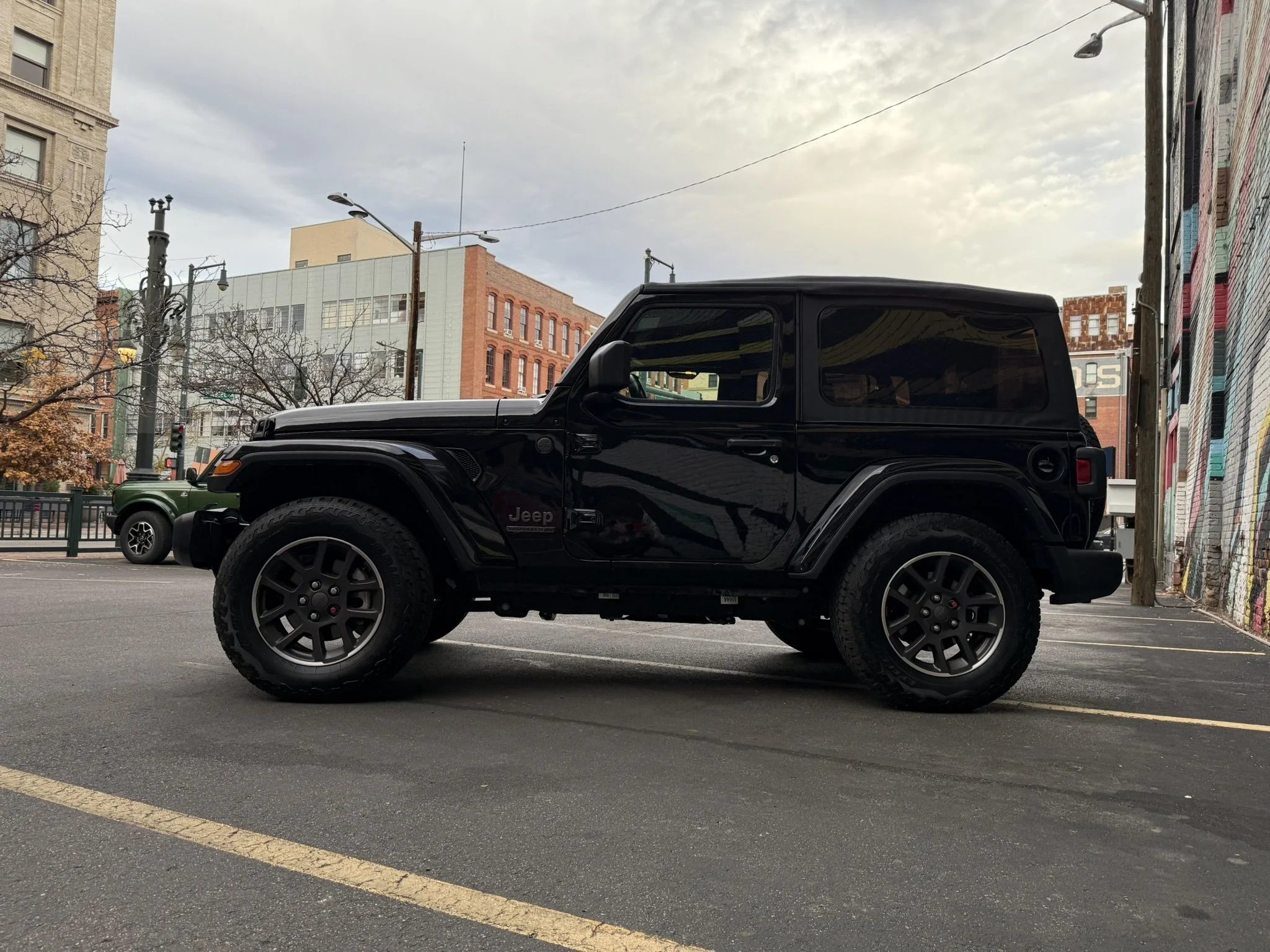 Black 2021 Jeep Wrangler 80th Anniversary Edition soft top rental parked on 16th Street Mall in downtown Denver, Colorado