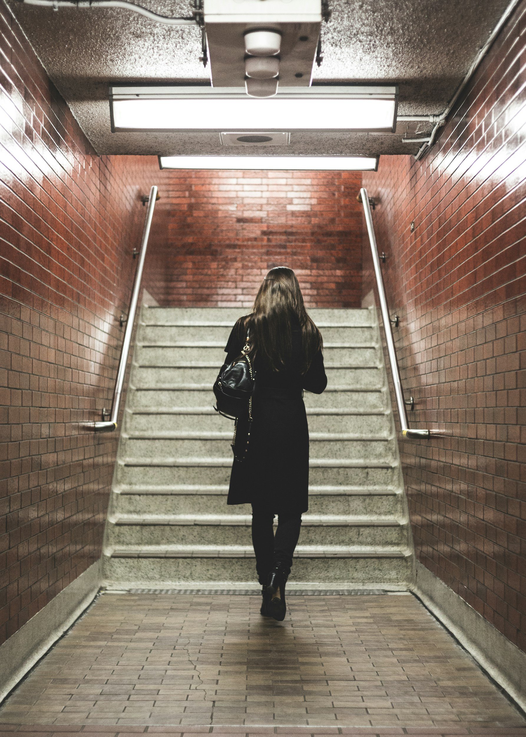 Woman walking up a staircase toward a subway exit, representing the decision to walk away from a grant opportunity as a deliberate strategy