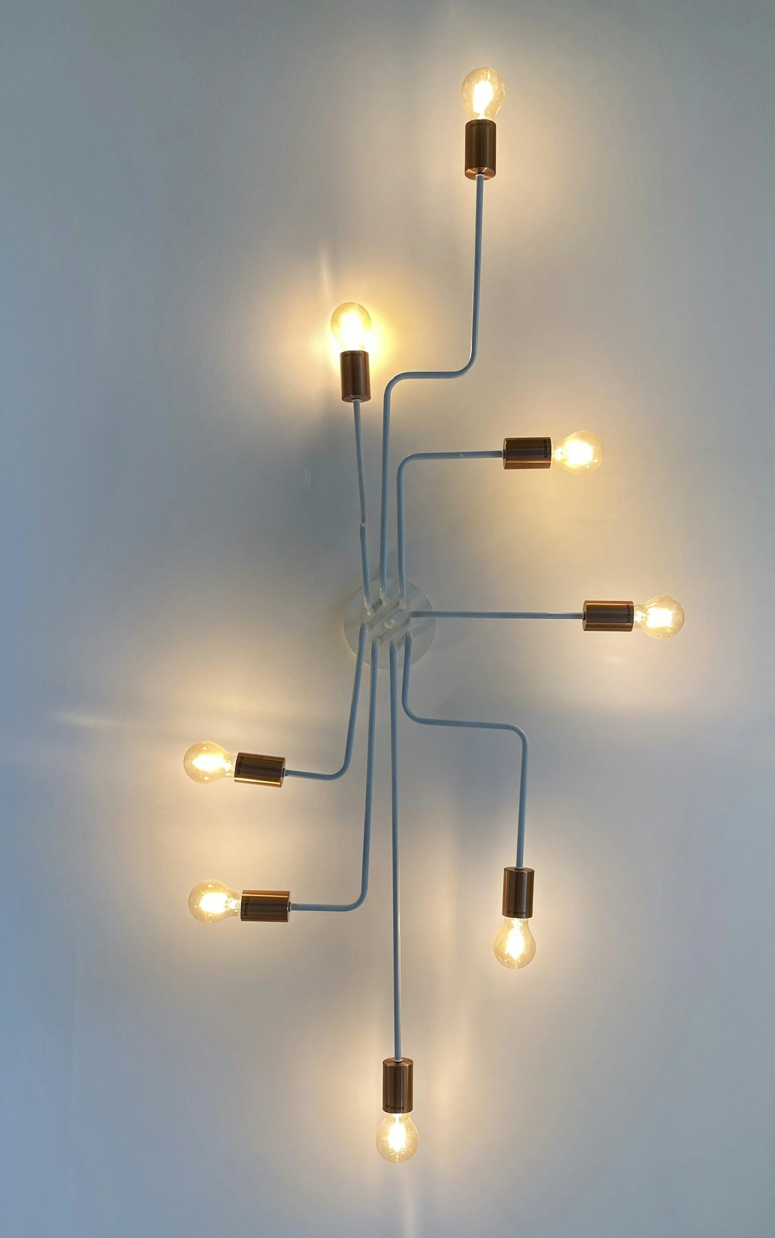 A ceiling light fixture with several bulbs on adjustable arms, each pointed in a different direction from a single base.
