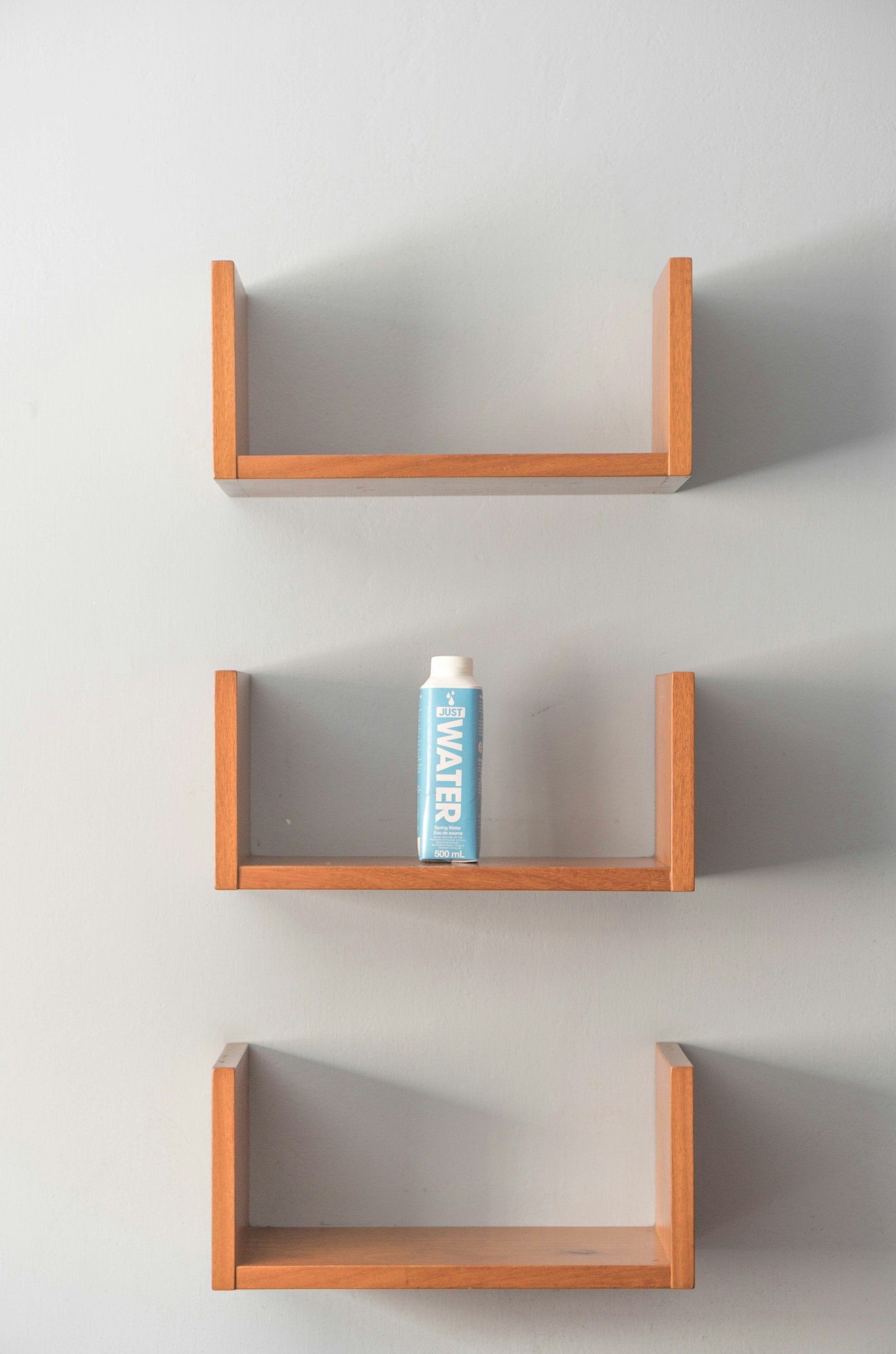 Empty wall shelves holding only a single water bottle
