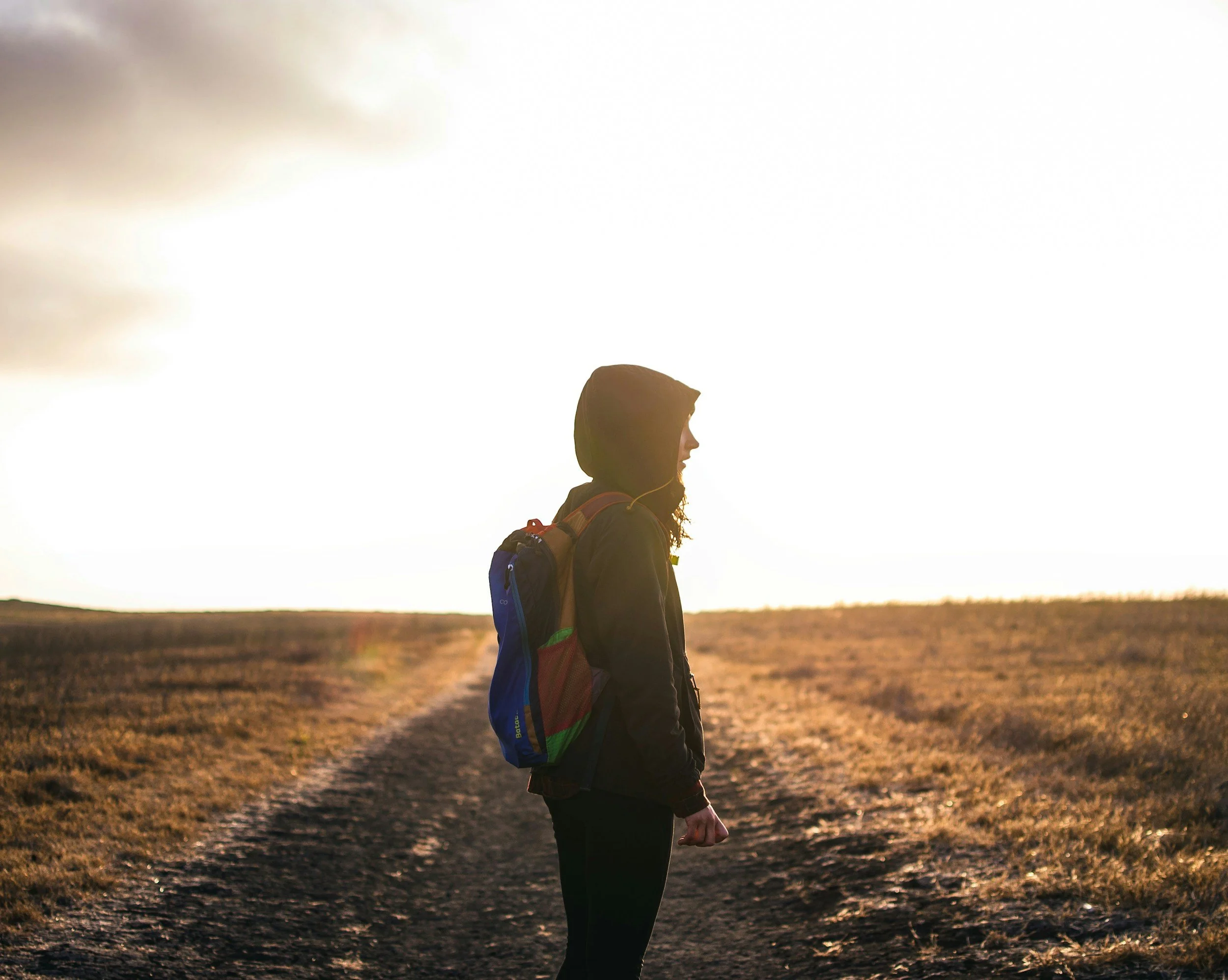 Person with backpack on a road in field