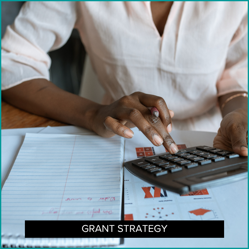 Woman using a calculator, representing the process of building a grant budget