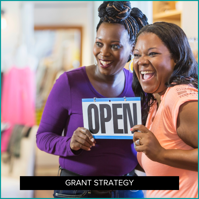 two women holding an "Open" sign for new business