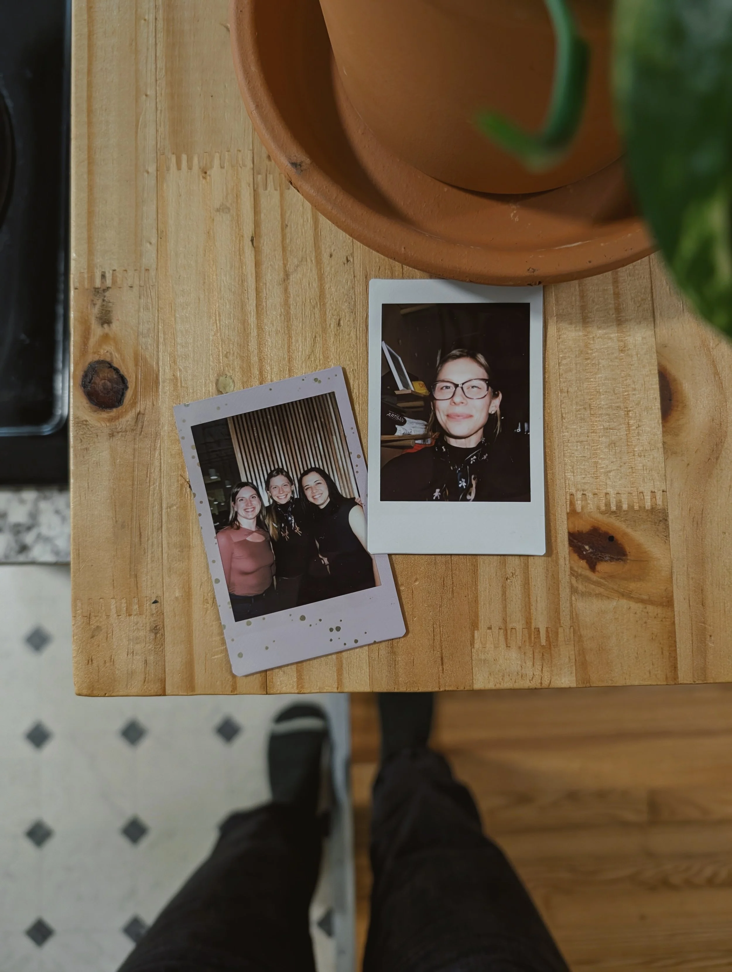 two mini polaroid photos sit on a wooden counter top