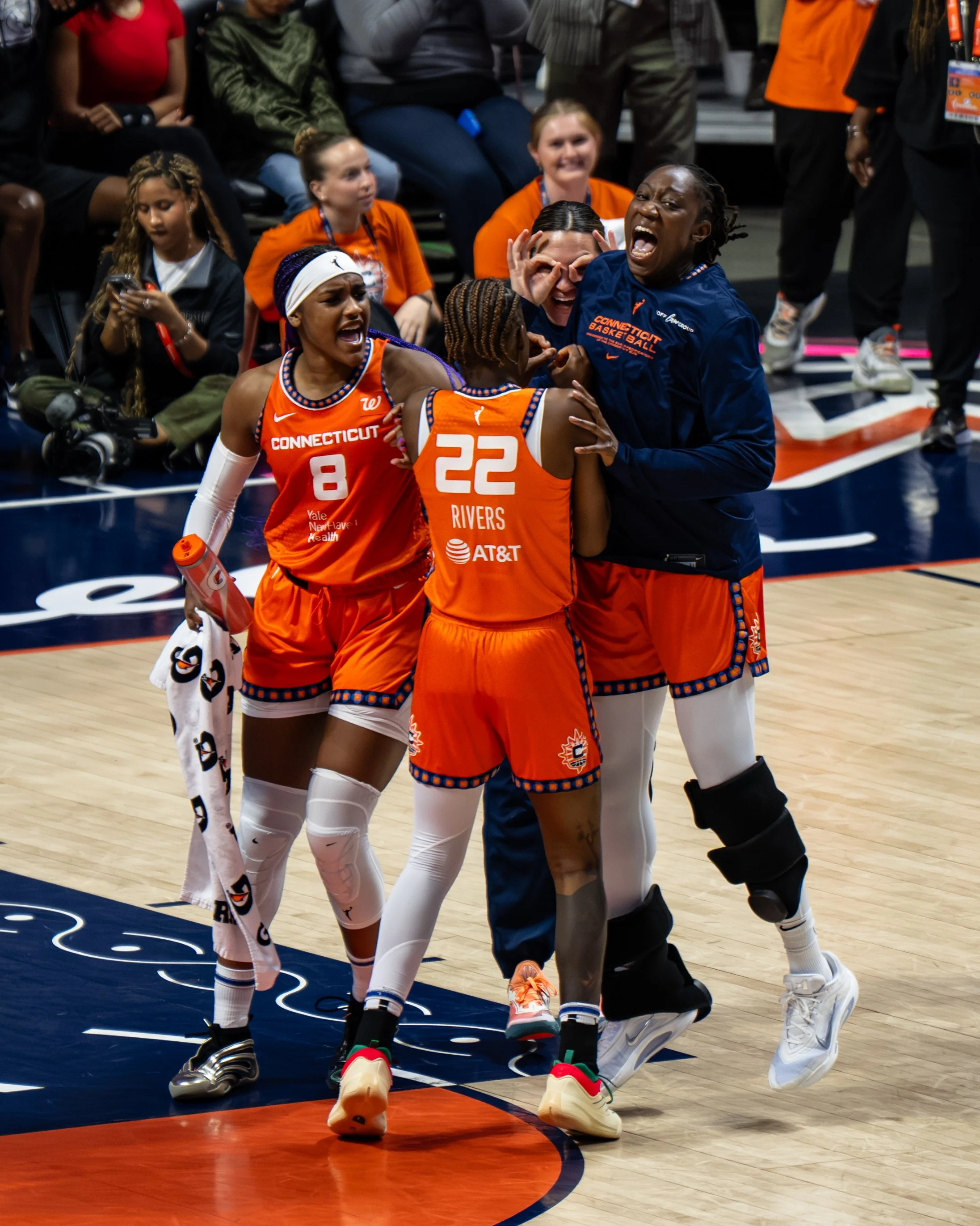 Celebrating women's basketball players from the Connecticut team on the court.