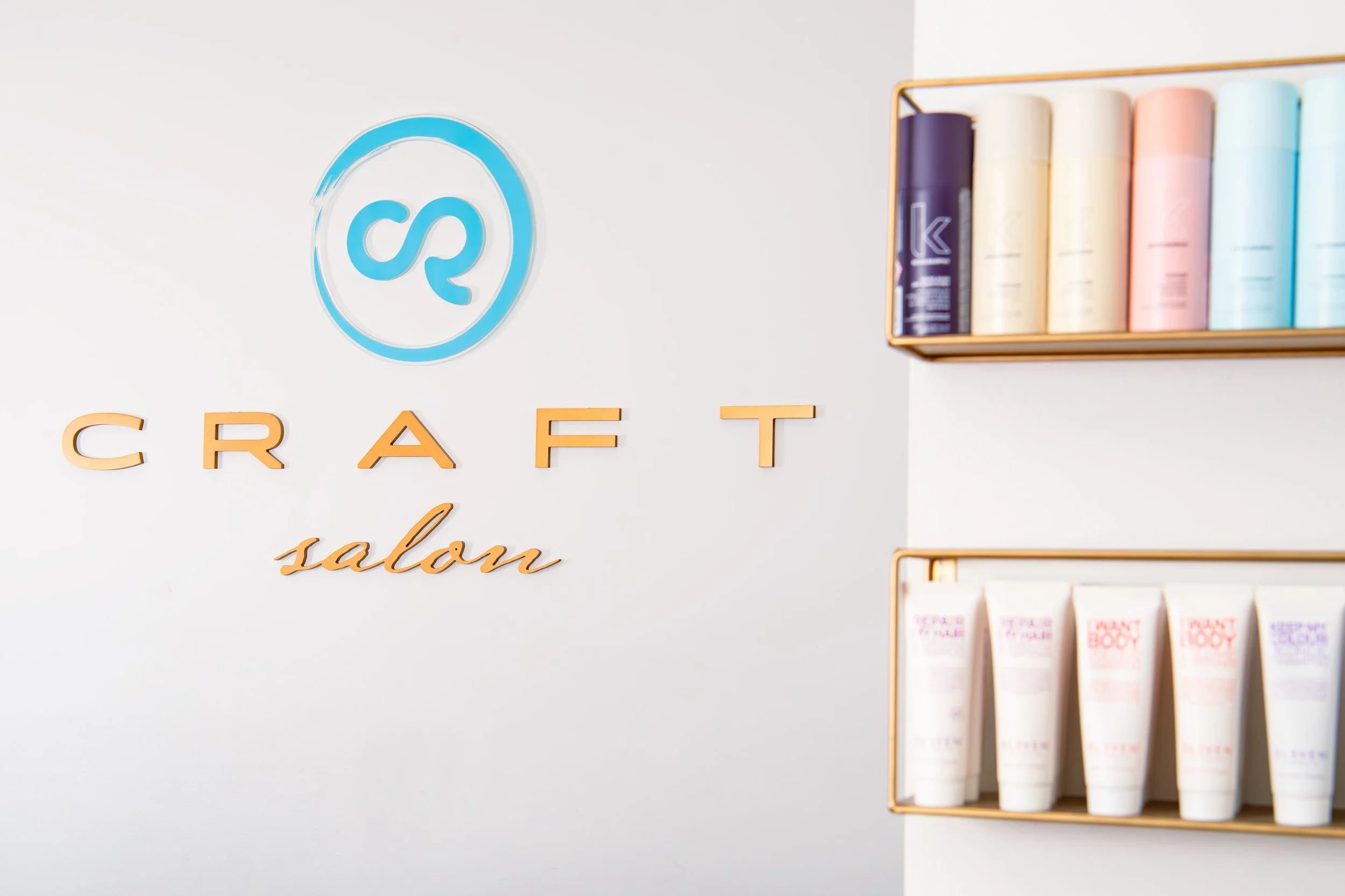 Interior of a craft salon with the words 'craft salon' on the wall and shelves displaying colorful bottles and tubes of hair or skincare products.