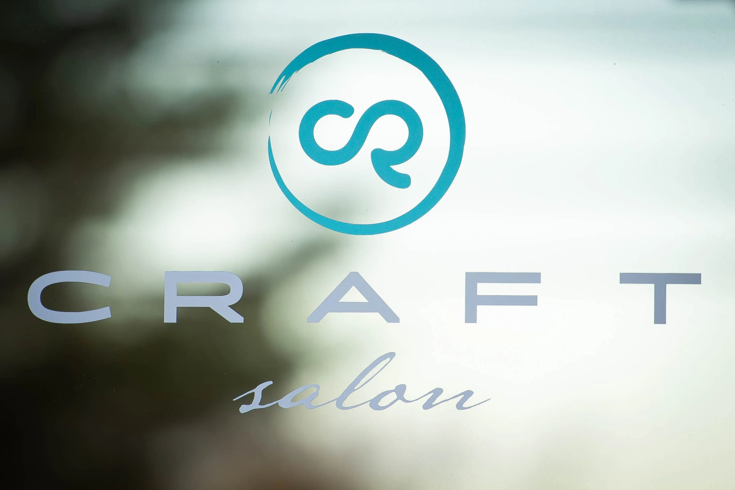 Glass door decal for craft salon with a circular logo featuring a stylized infinity symbol and the words 'CRAFT salon' written below, with 'salon' in cursive.