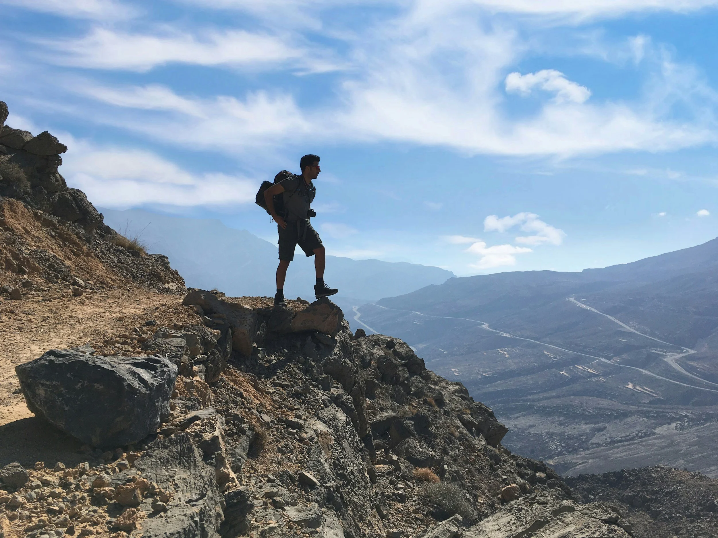 Hiker standing on a mountain summit feeling energized, embodying the cellular power and stamina from NAD+ infusion.