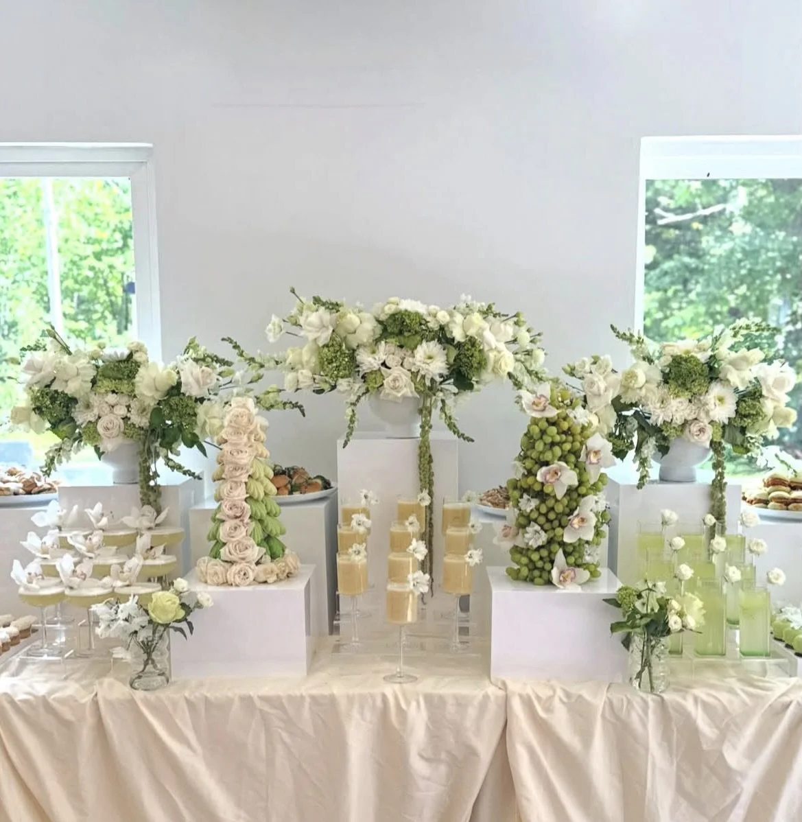 Décor de table de mariage avec des arrangements floraux blancs et des fruits verts.