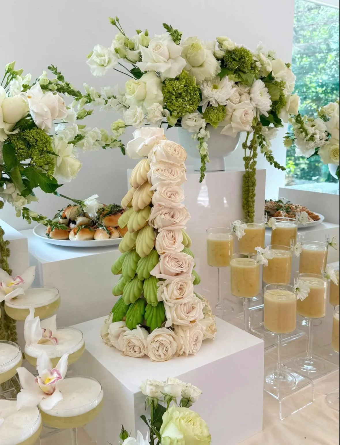 Arrangement floral blanc avec roses, pivoines, et hortensias, et desserts en petites coupes et biscuits sur une table.