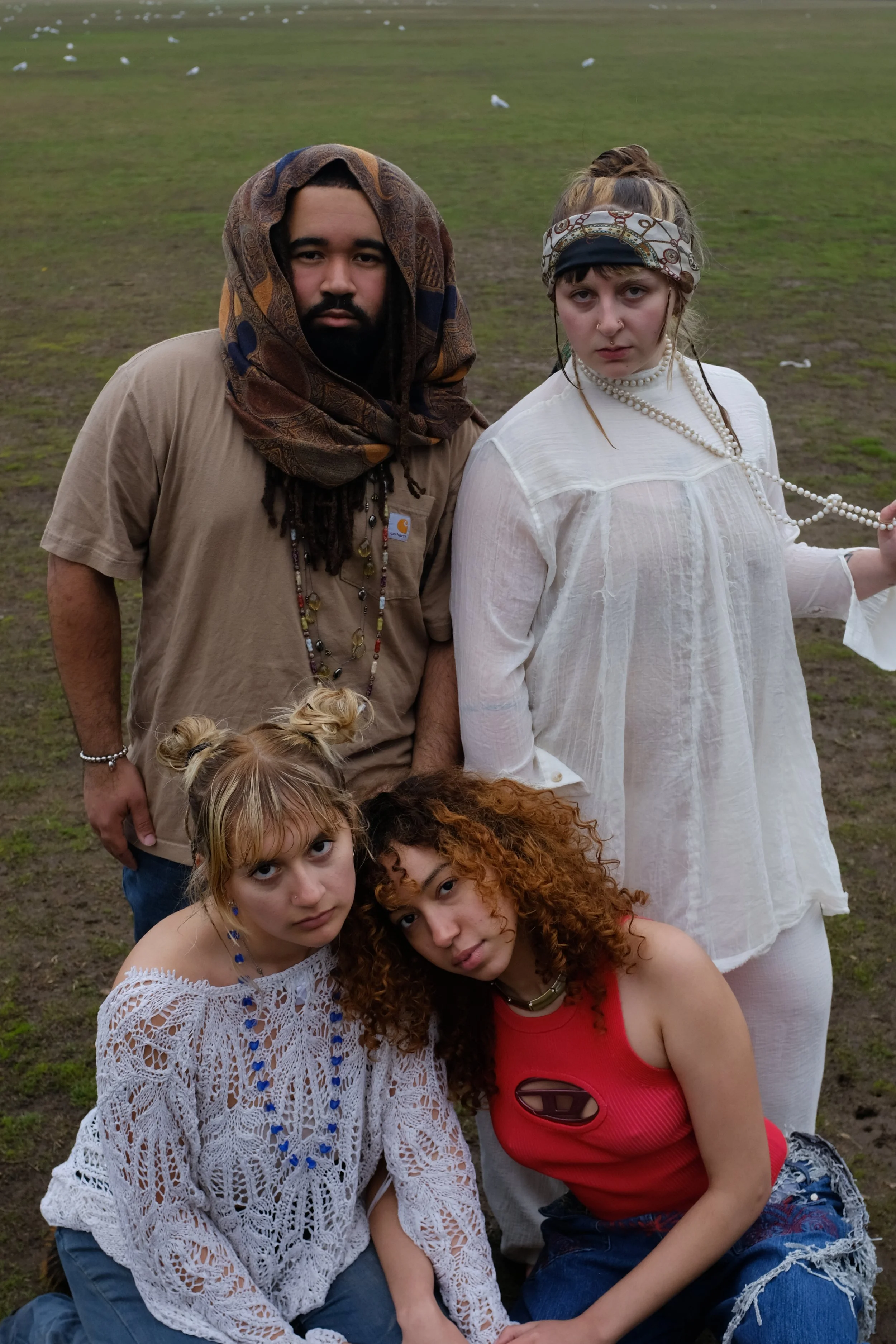 Group of five young adults posing on a grassy field.