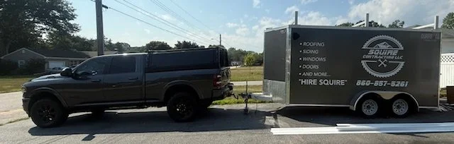 A black pickup truck attached to a trailer with the logo for Square Source LLC and text listing services including roofing, siding, windows, doors, and more.