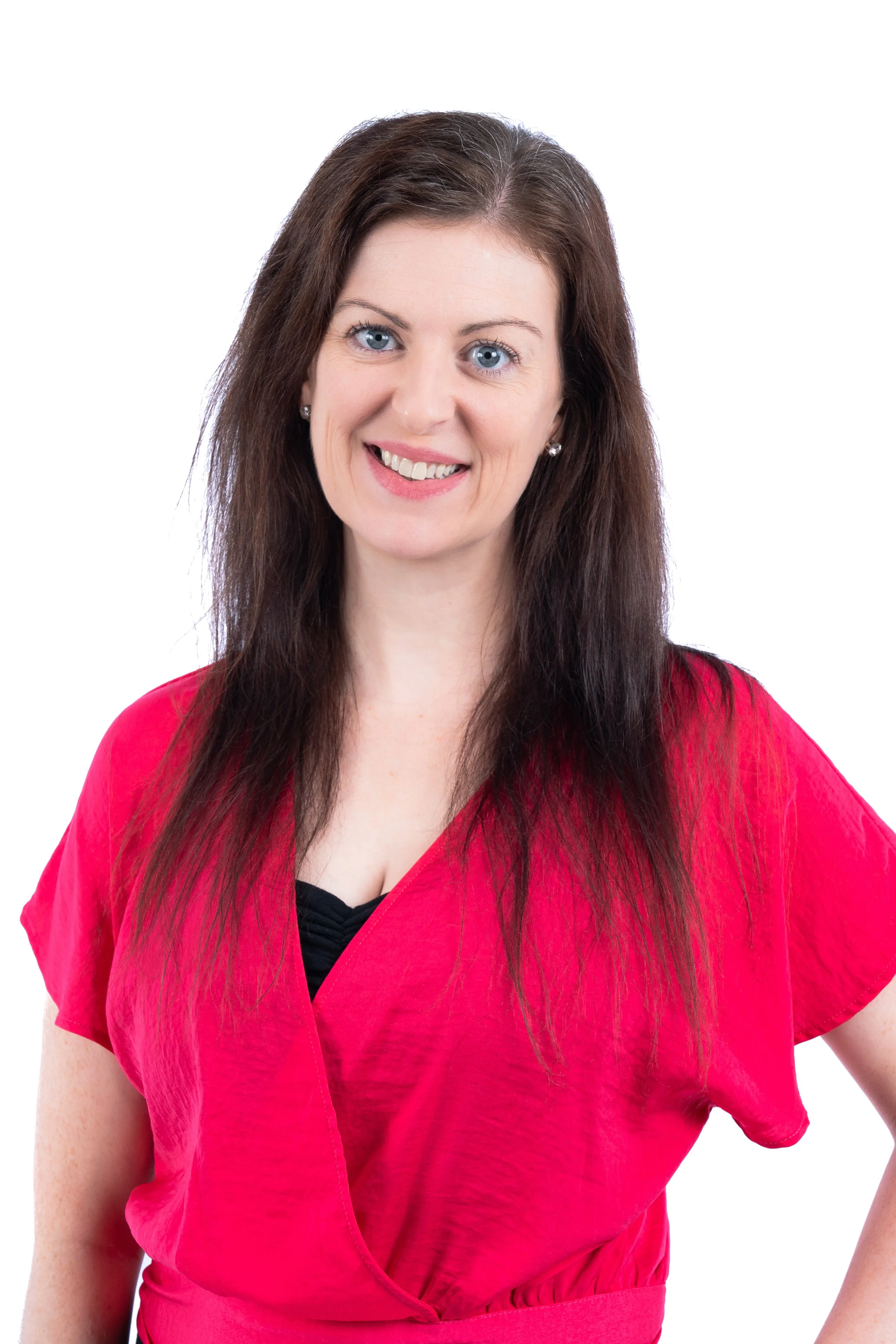 A woman with long dark hair and blue eyes smiling, wearing a bright pink top against a white background.