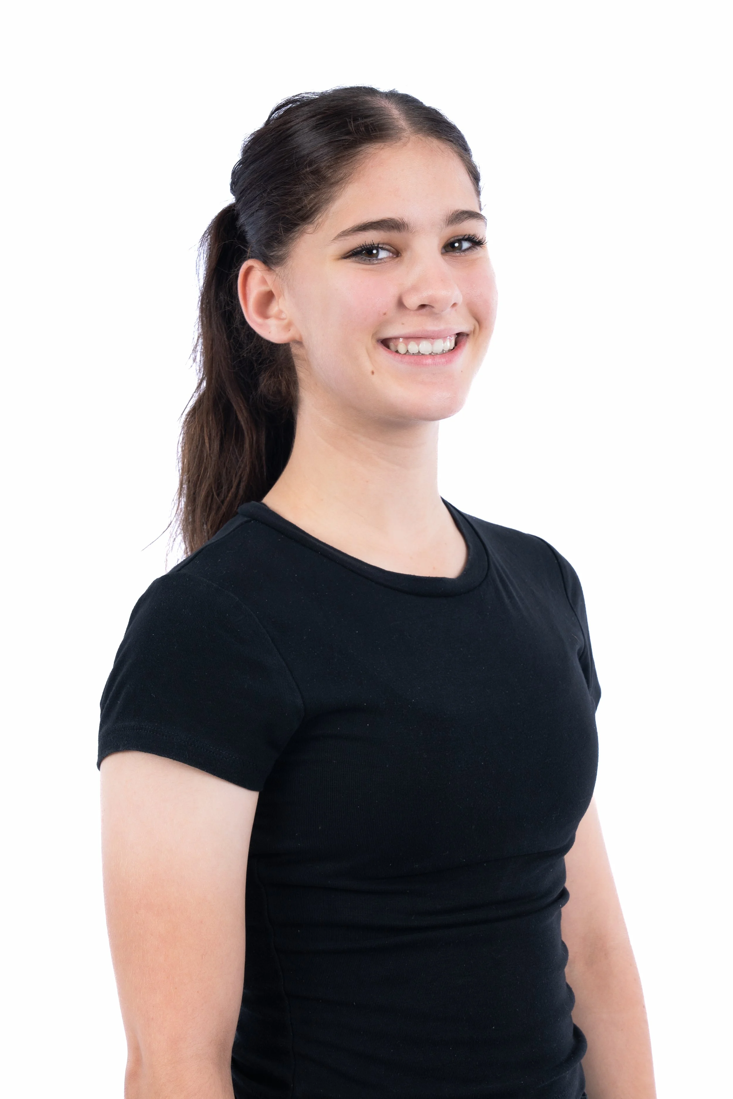 A young woman with long brown hair tied back in a ponytail, smiling, wearing a black t-shirt, standing against a white background.