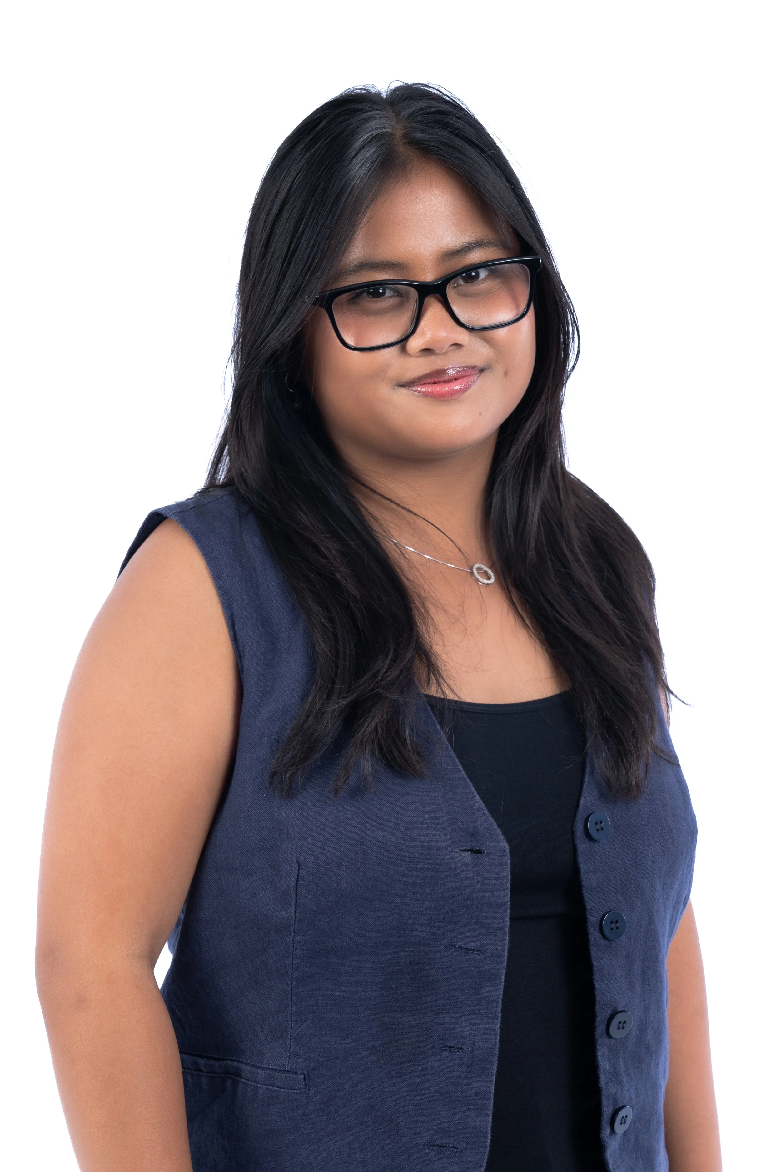 A young woman with long dark hair, glasses, wearing a navy vest over a black top and a silver necklace.