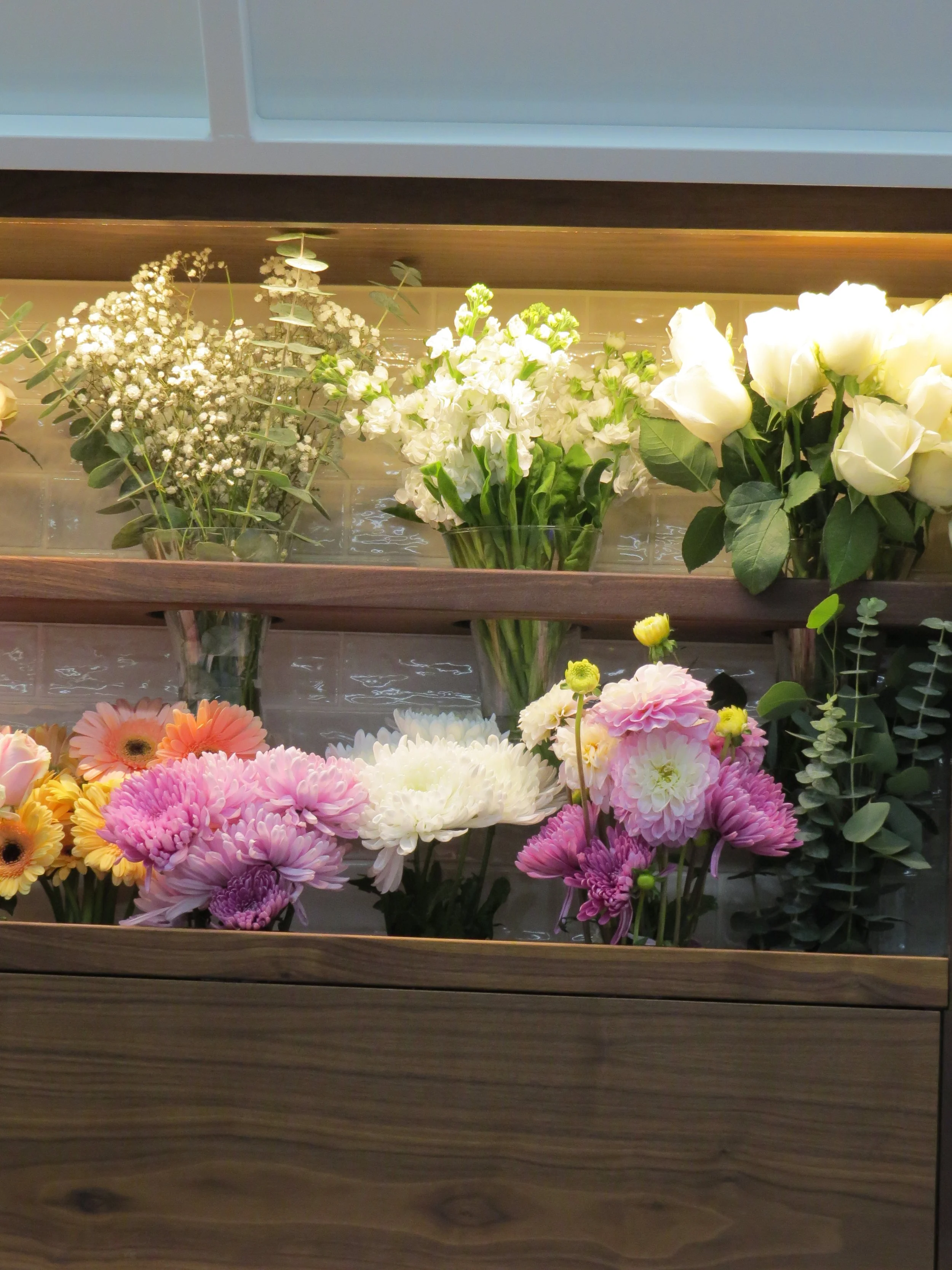A pink and white bouquet of dried and preserved flowers wrapped in pink paper with a pink ribbon.