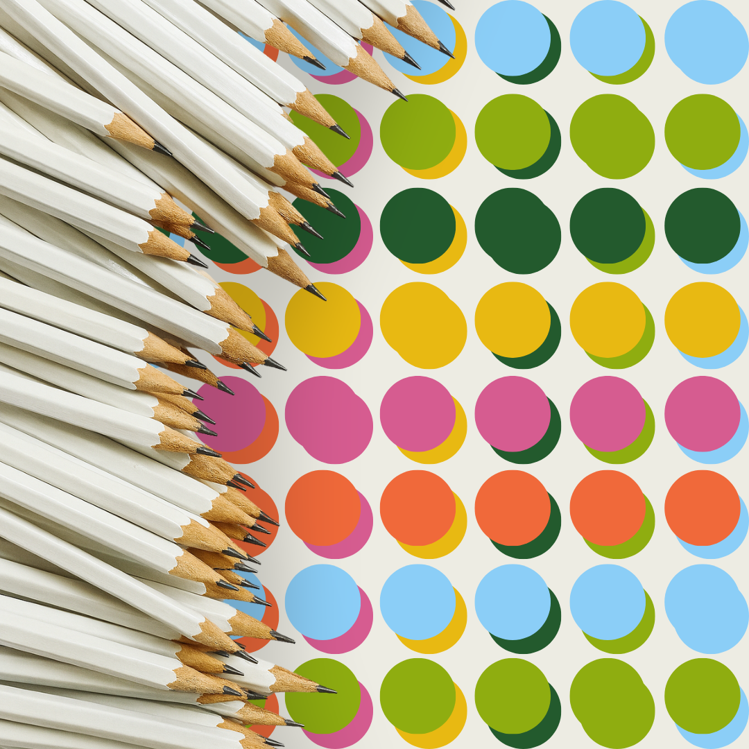 A group of white pencils with black tips on a polka dot background of various colors.