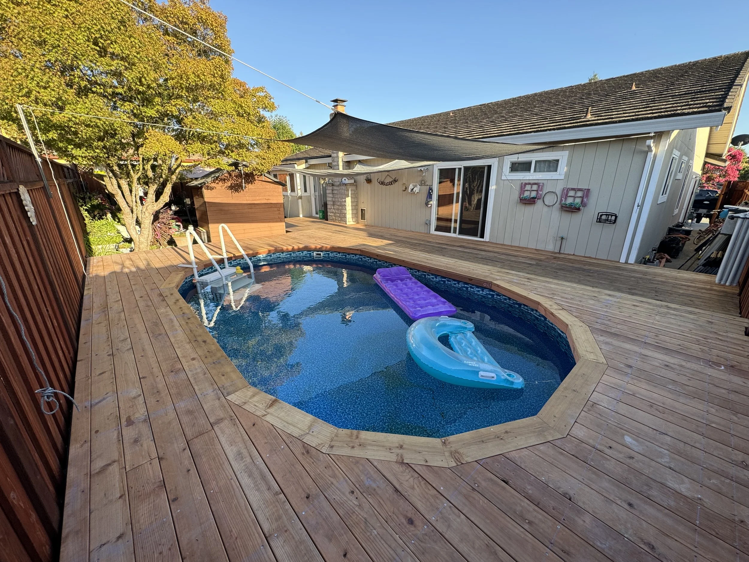 Backyard deck around in ground pool.
