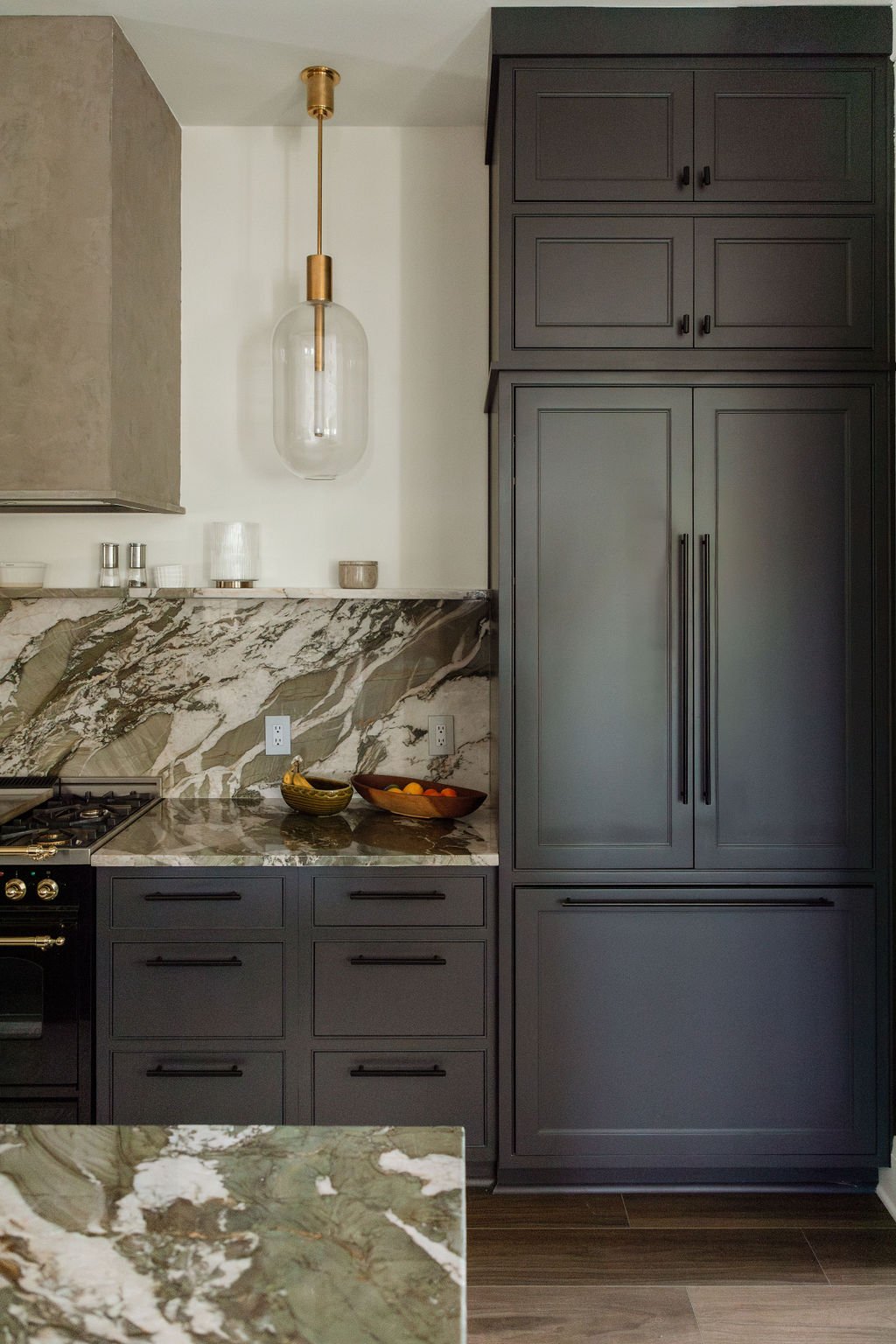 Close-up of dark kitchen cabinetry with marble countertops and backsplash by Pinehurst, NC interior designer.