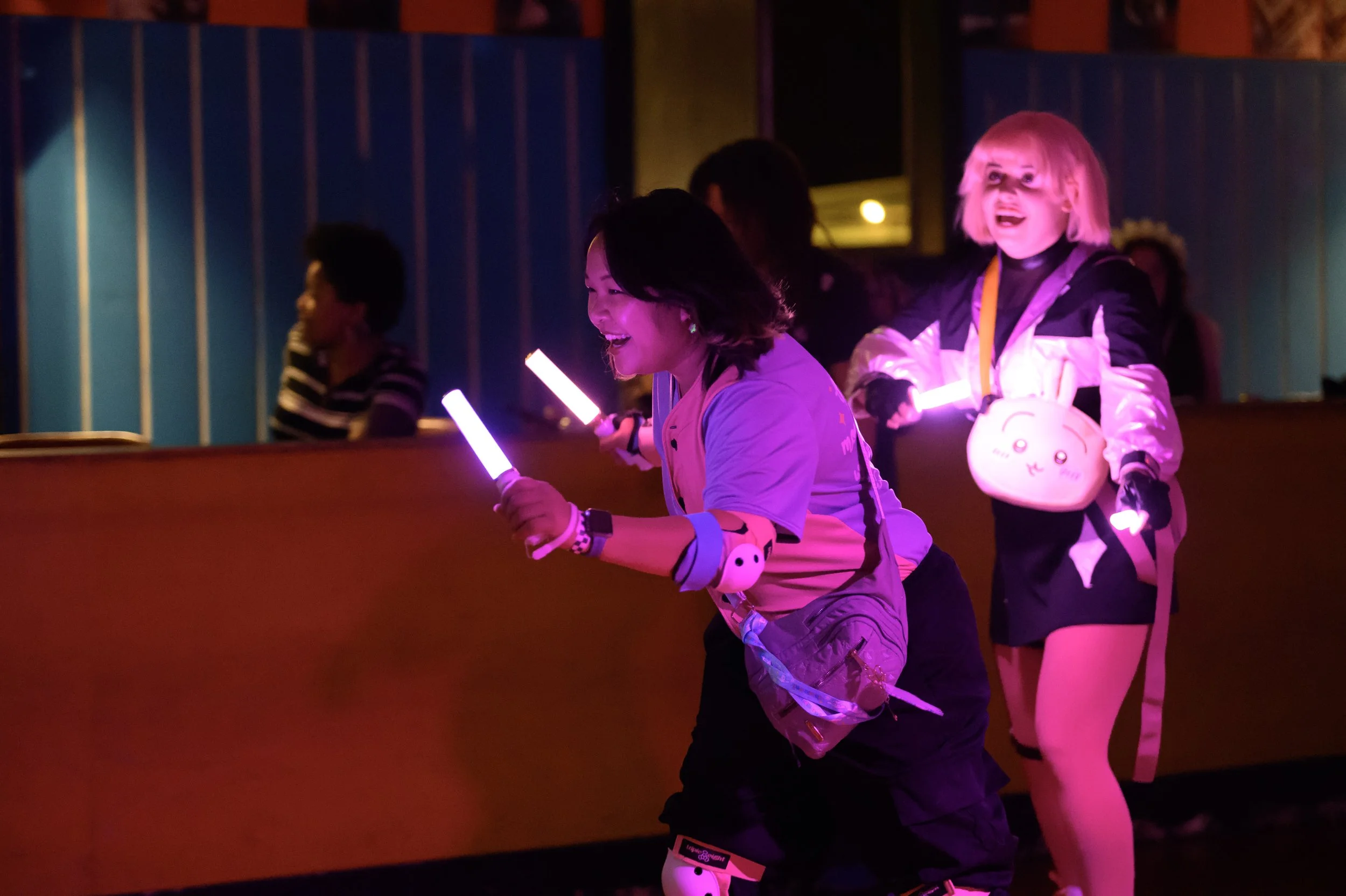 Group of young women and children enjoying glow stick dance party at night with colorful lights