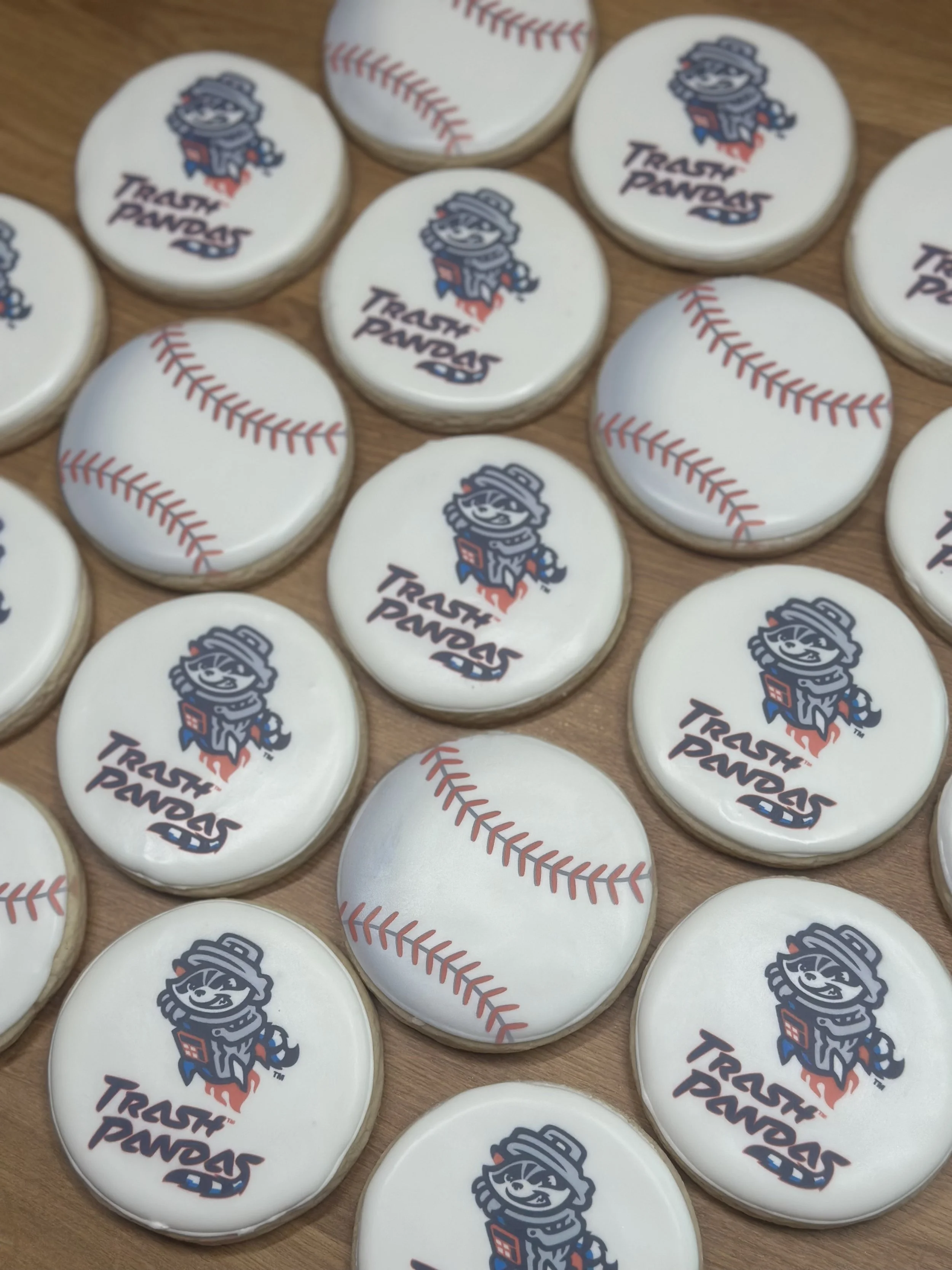 Cookies decorated with Trash Pandas logo and baseball stitching pattern on white icing.