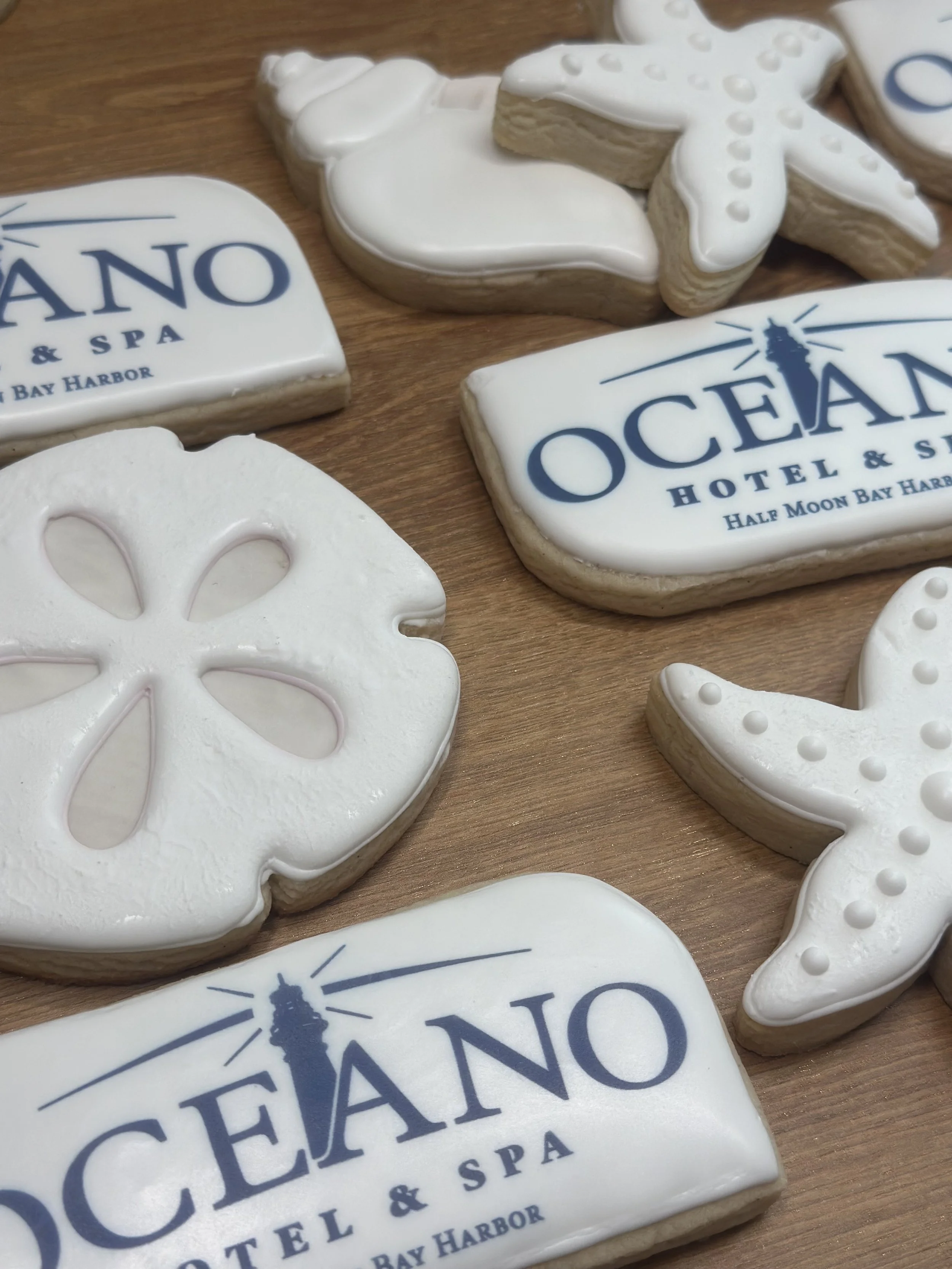 Decorative cookies with the Ocean Hotel & Spa Half Moon Bay Harbor logo and ocean-themed shapes like starfish and shells.