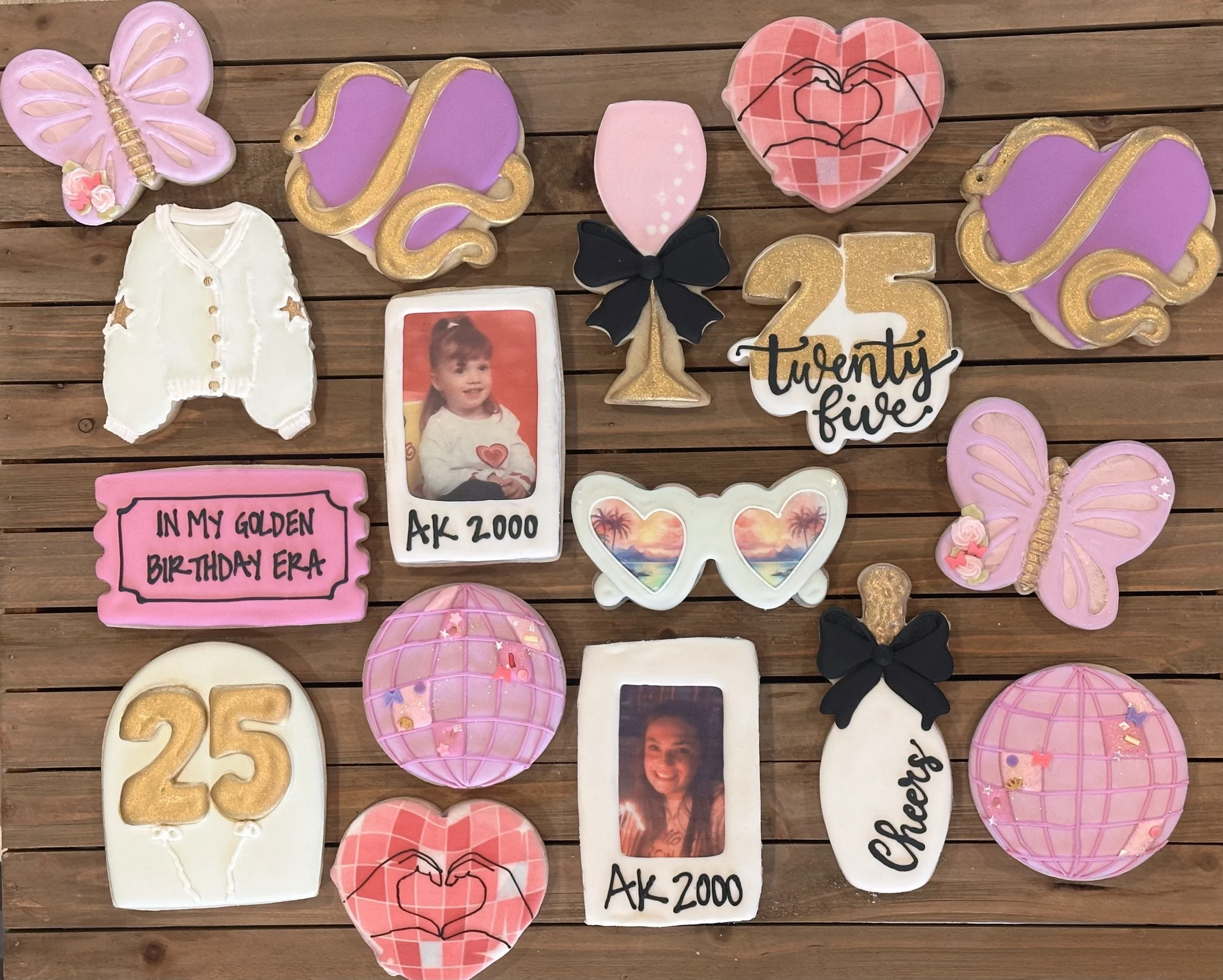 Assorted decorated cookies on a wooden surface, including butterflies, balloons, hearts, sunglasses, a girl’s photo, a champagne glass, a number 25, a number 25, and a bottle, celebrating a 25th birthday.
