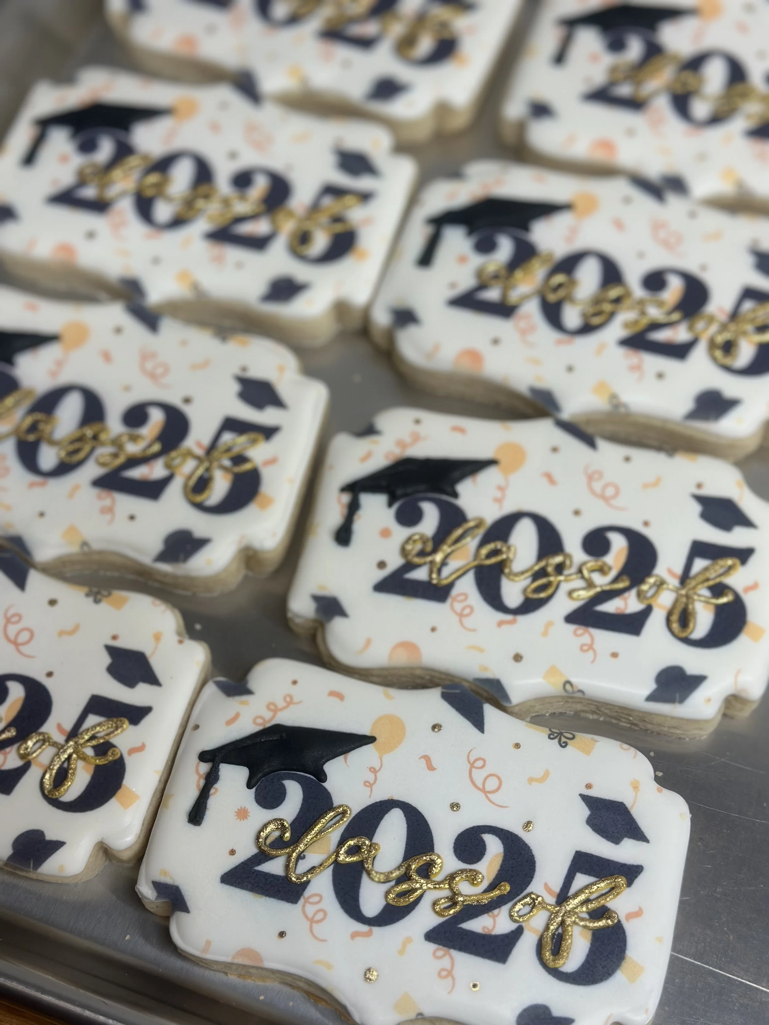 Cookies decorated with 'Class of 2023' and graduation cap designs, in celebration of graduation.