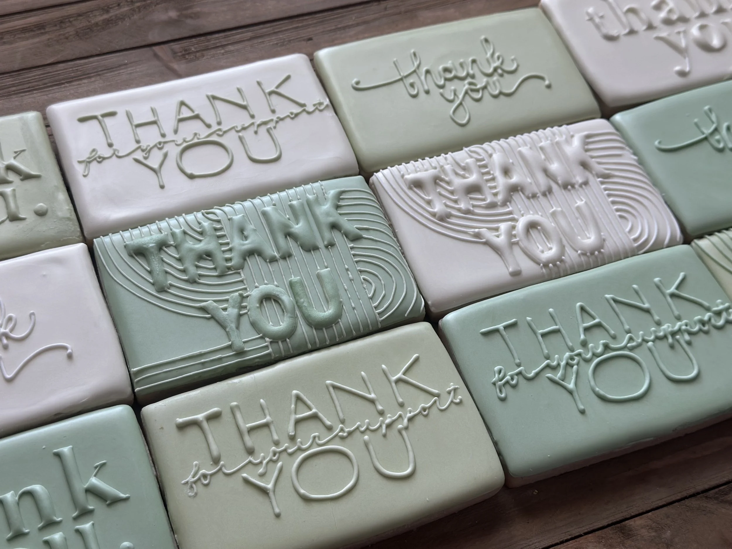 Decorative soap bars with embossed messages of thanks and appreciation, arranged on a wooden surface.