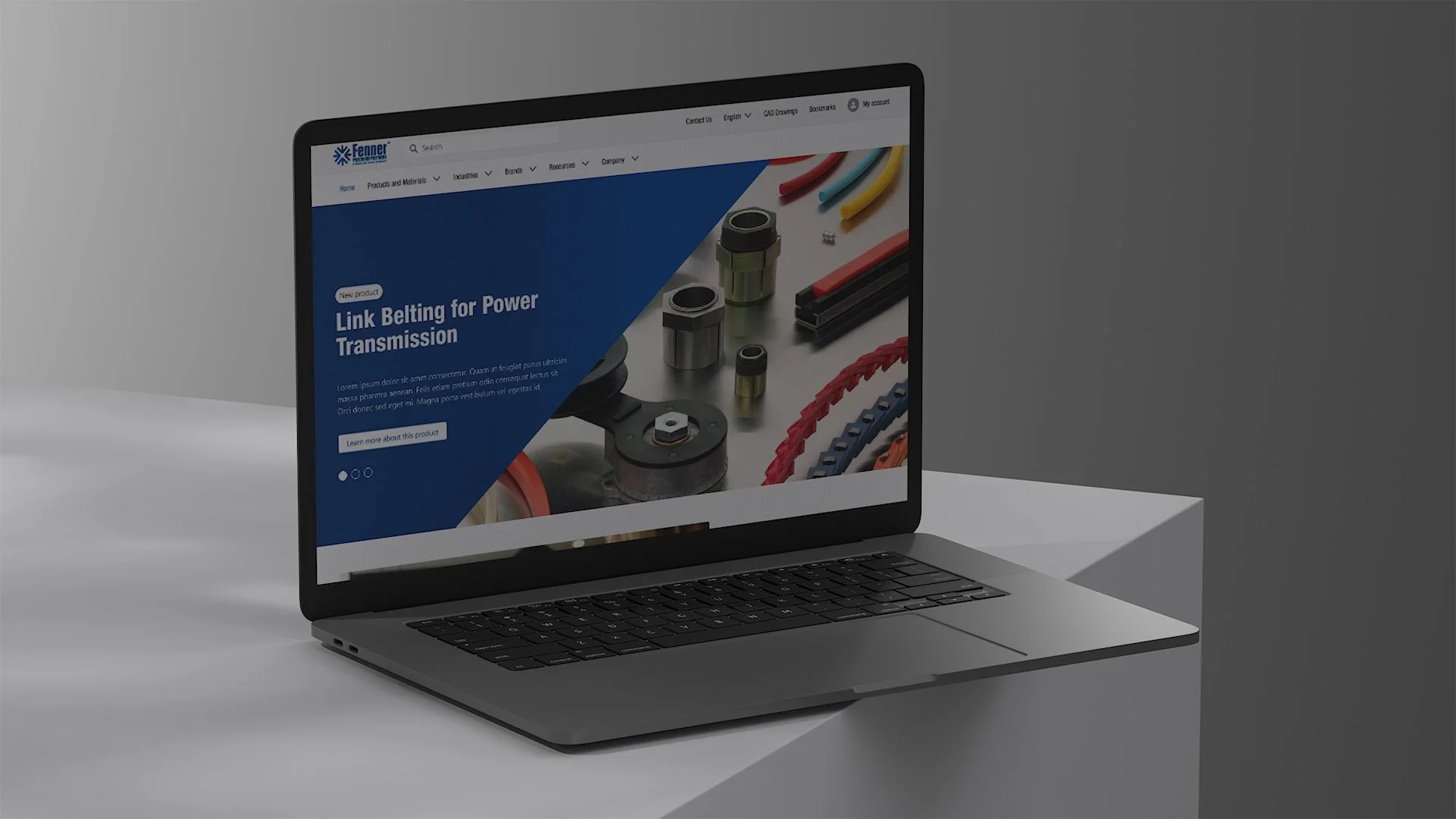 Open laptop on a white table displaying a webpage for Fenner, featuring images of electrical components and power transmission products.