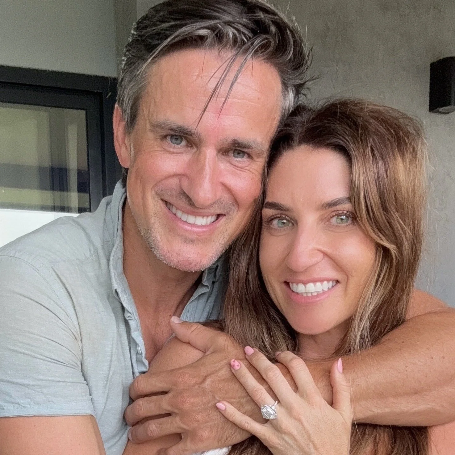 A smiling man with gray hair and a woman with long brown hair in an embrace, both displaying happiness.