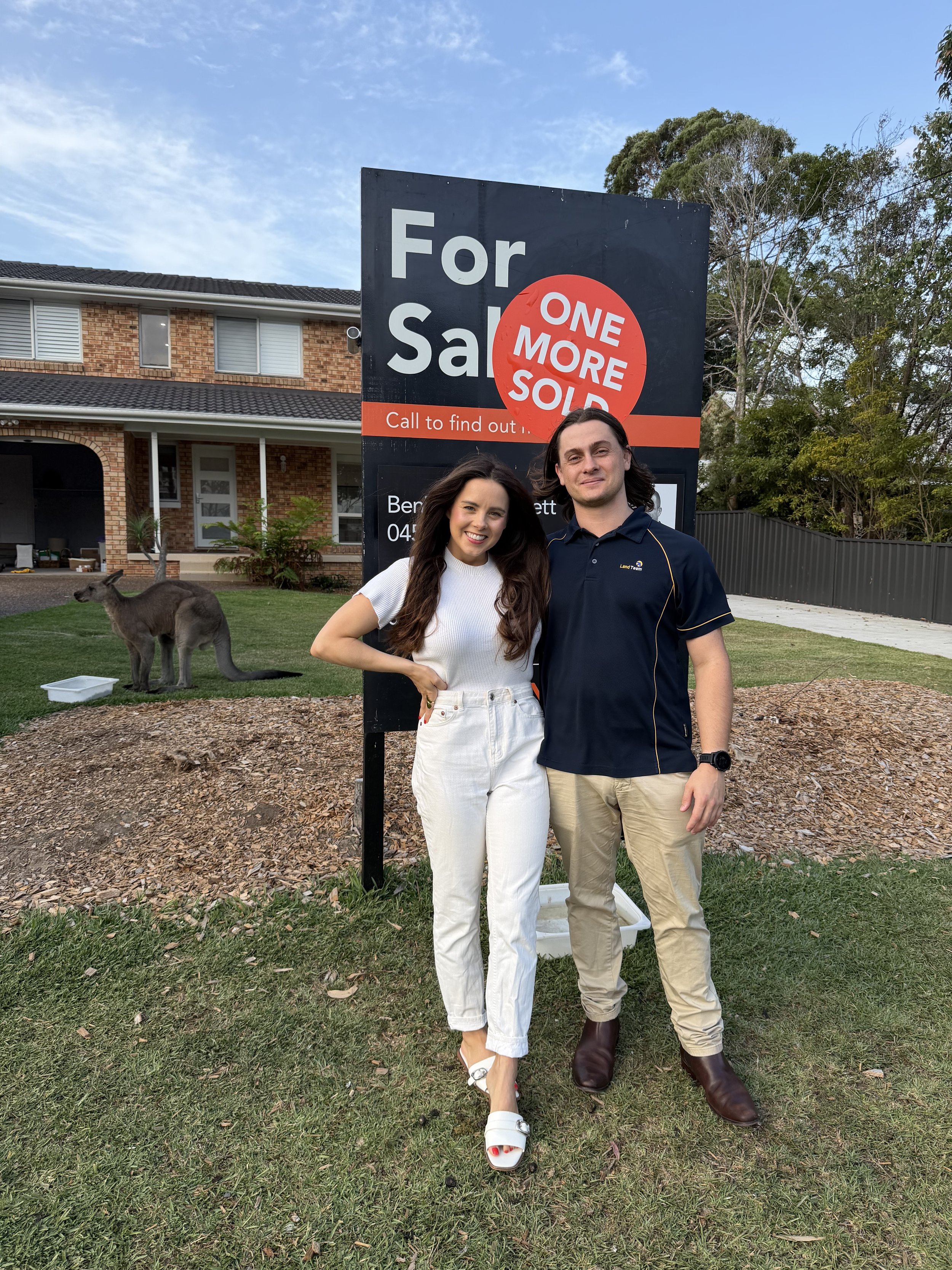 couple standing in front of sold sign