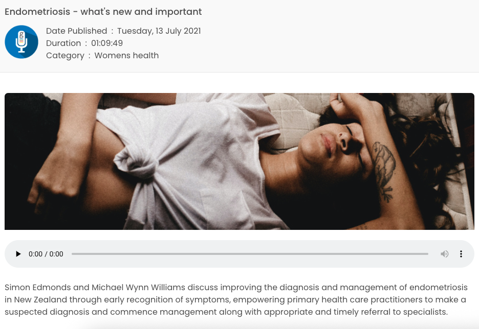 A woman lying down with her eyes closed, wearing a white T-shirt, showing her arm with tattoos.