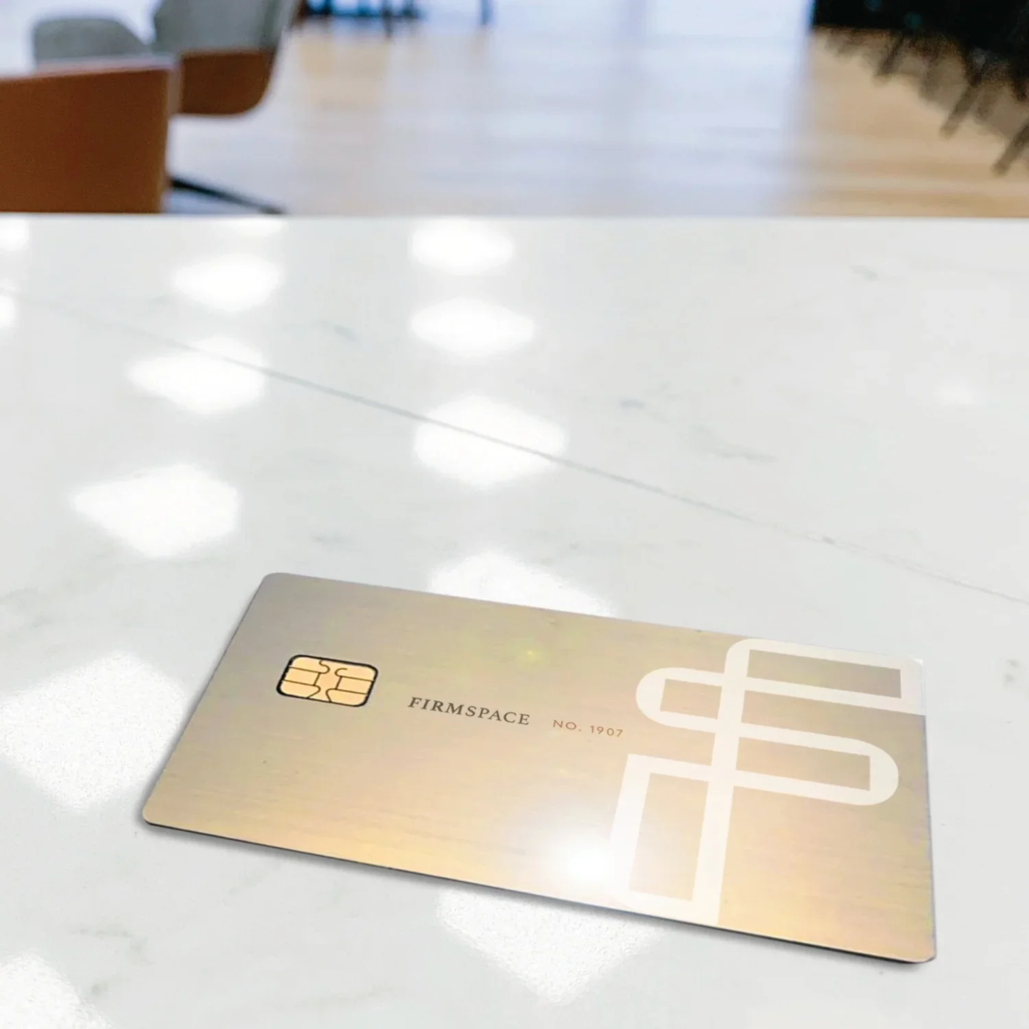 A gold-colored Firmspace credit card lying flat on a white table in a well-lit room.