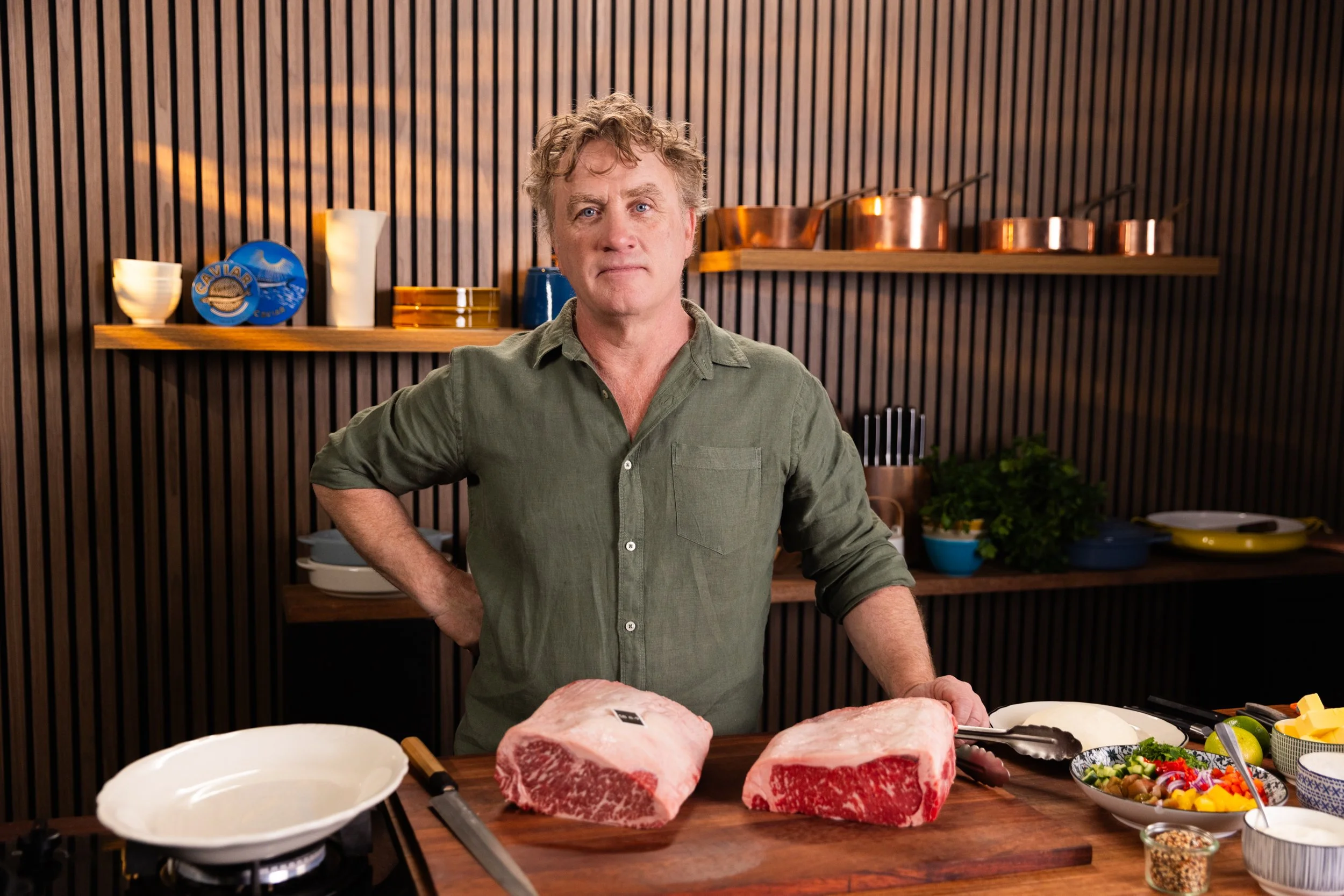 Chef AdrIan Richardson in the kitchen with sides of beef on a chopping board
