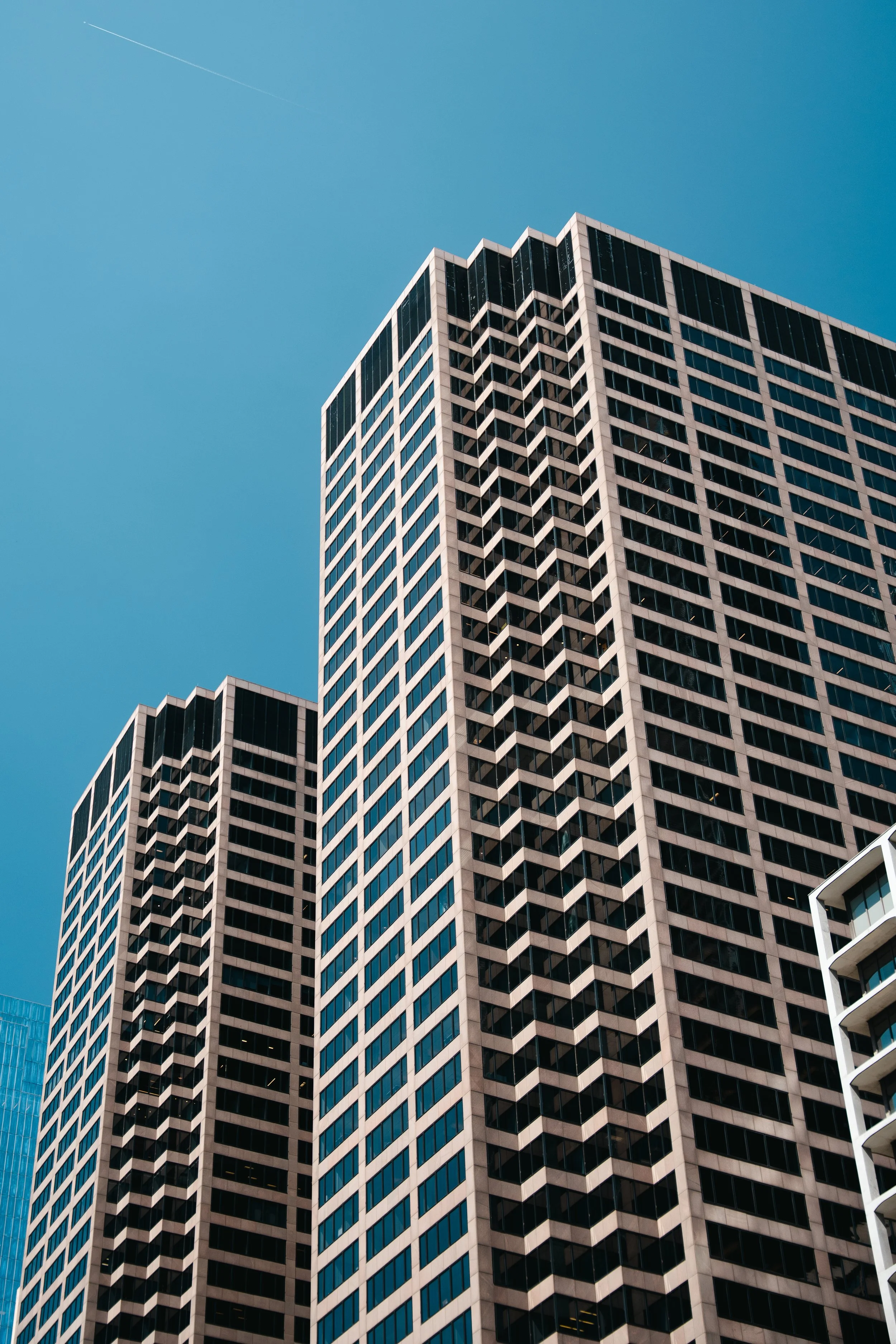 Tall modern skyscraper with many windows against a clear blue sky.