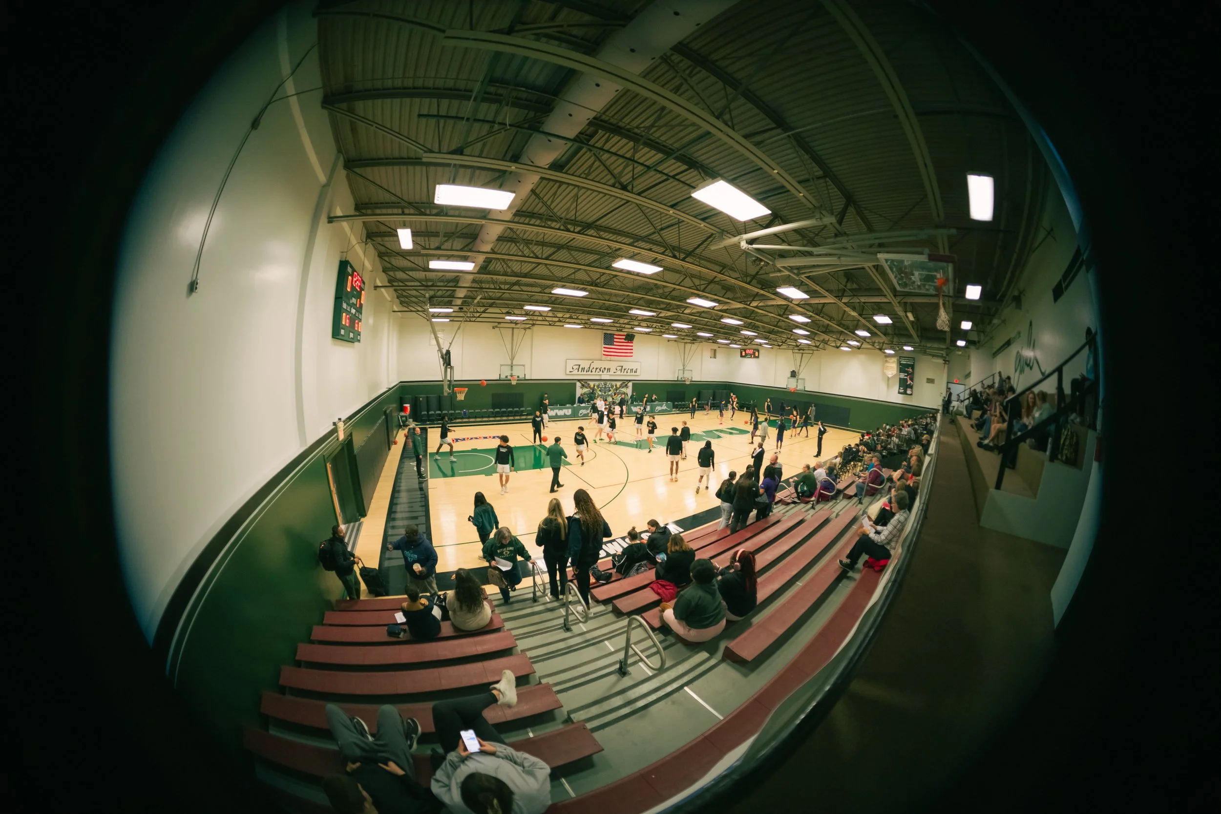 View of a basketball game in Anderson Arena with players on the court and spectators in the bleachers.