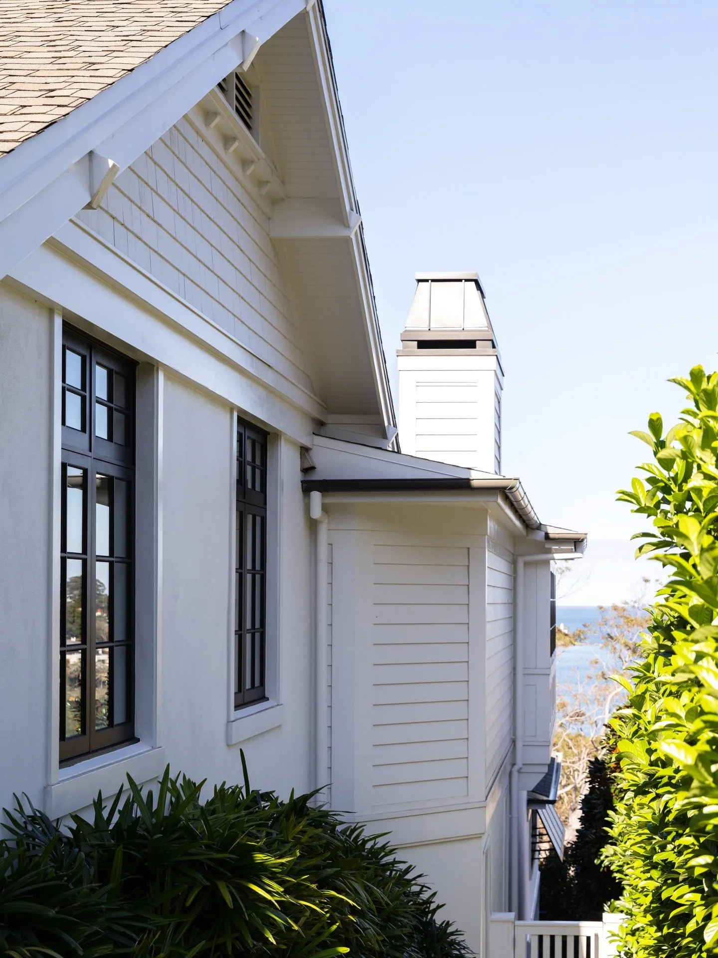 Exterior detailing at our Chinaman&rsquo;s Beach, Mosman project pairs classic weatherboards and custom timber windows with timeless elements including a gable vent with toothing detail, a bespoke chimney cap and asphalt shingle roof. A timber gate o