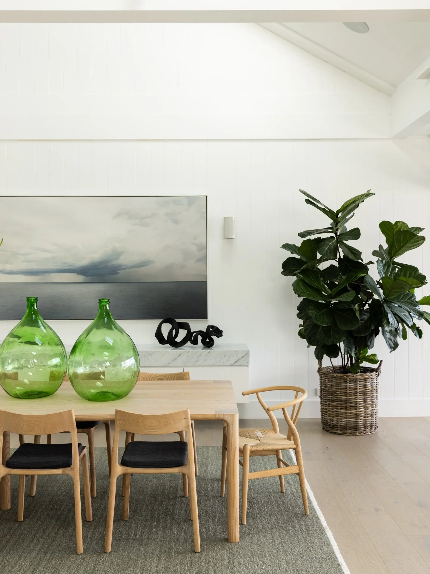 &lsquo;Sea in Blue and Violet&rsquo; by Chris Langlois anchors the dining room with depth and mood, while a textural wall covering by Maeve Pacheco adds softness to the adjoining wall. The Molly dining table and chairs by Adam Goodrum were custom cra