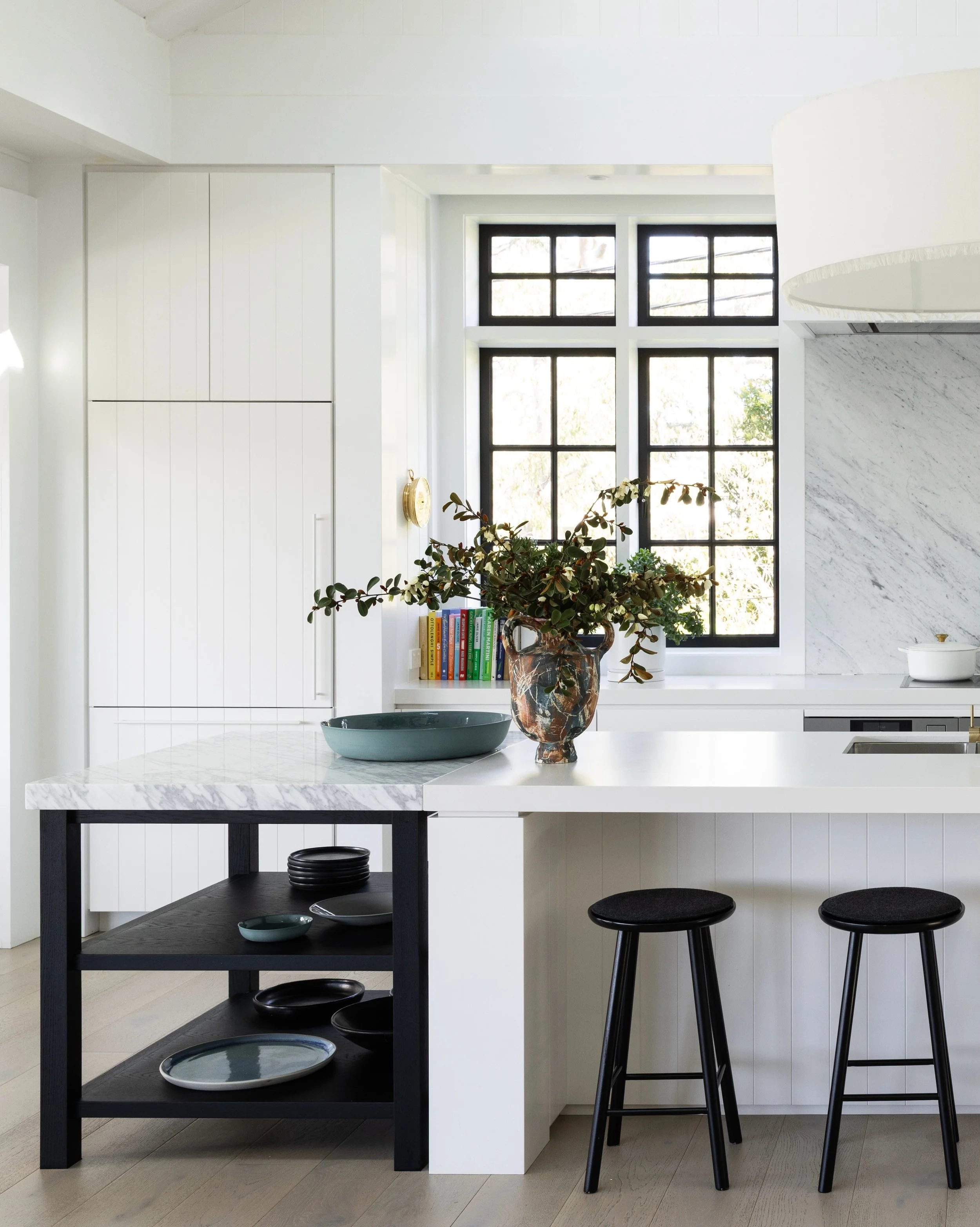 At the heart of the home, this light filled open plan kitchen was designed to embrace both connection and outlook, with sweeping views through the living spaces to the water beyond. Project @strittdesignandconstruction. Styling @olgalewisstyling. Pho